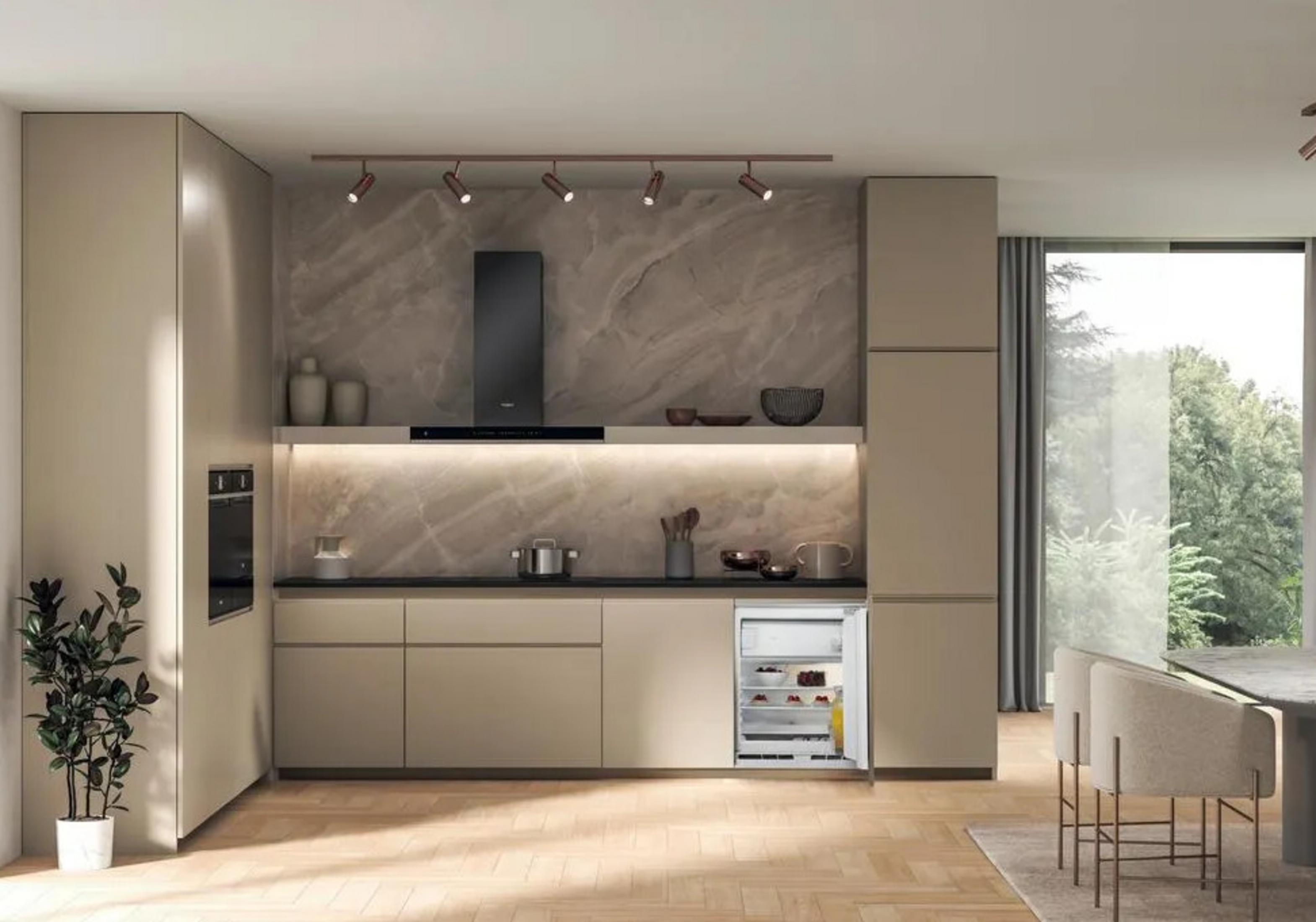 Cucina moderna con mobili beige, cappa nera e mini-frigo pieno di cibo.