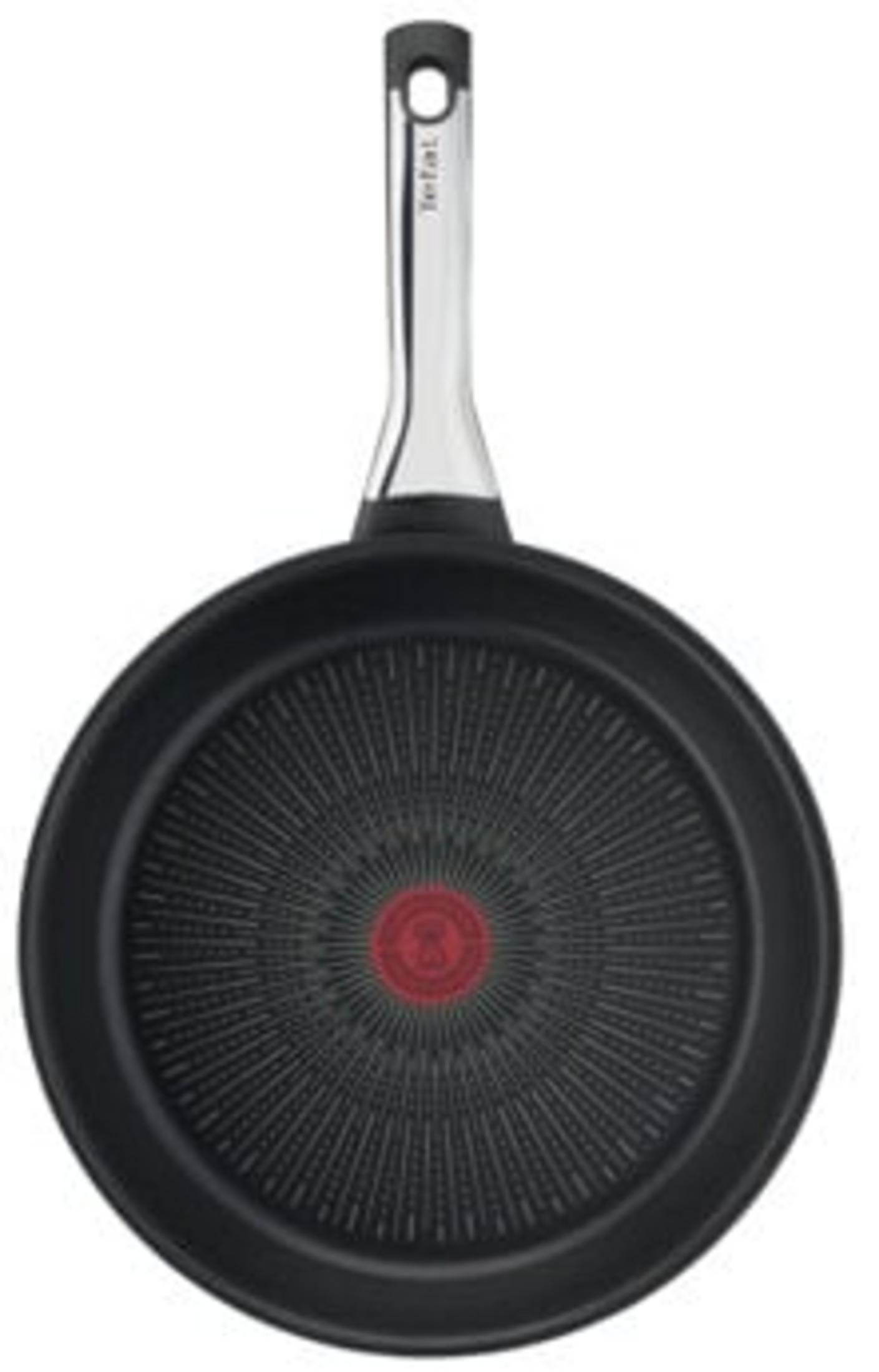 Gümüş saplı siyah tava, ortasında kırmızı T-fal logosu bulunur.