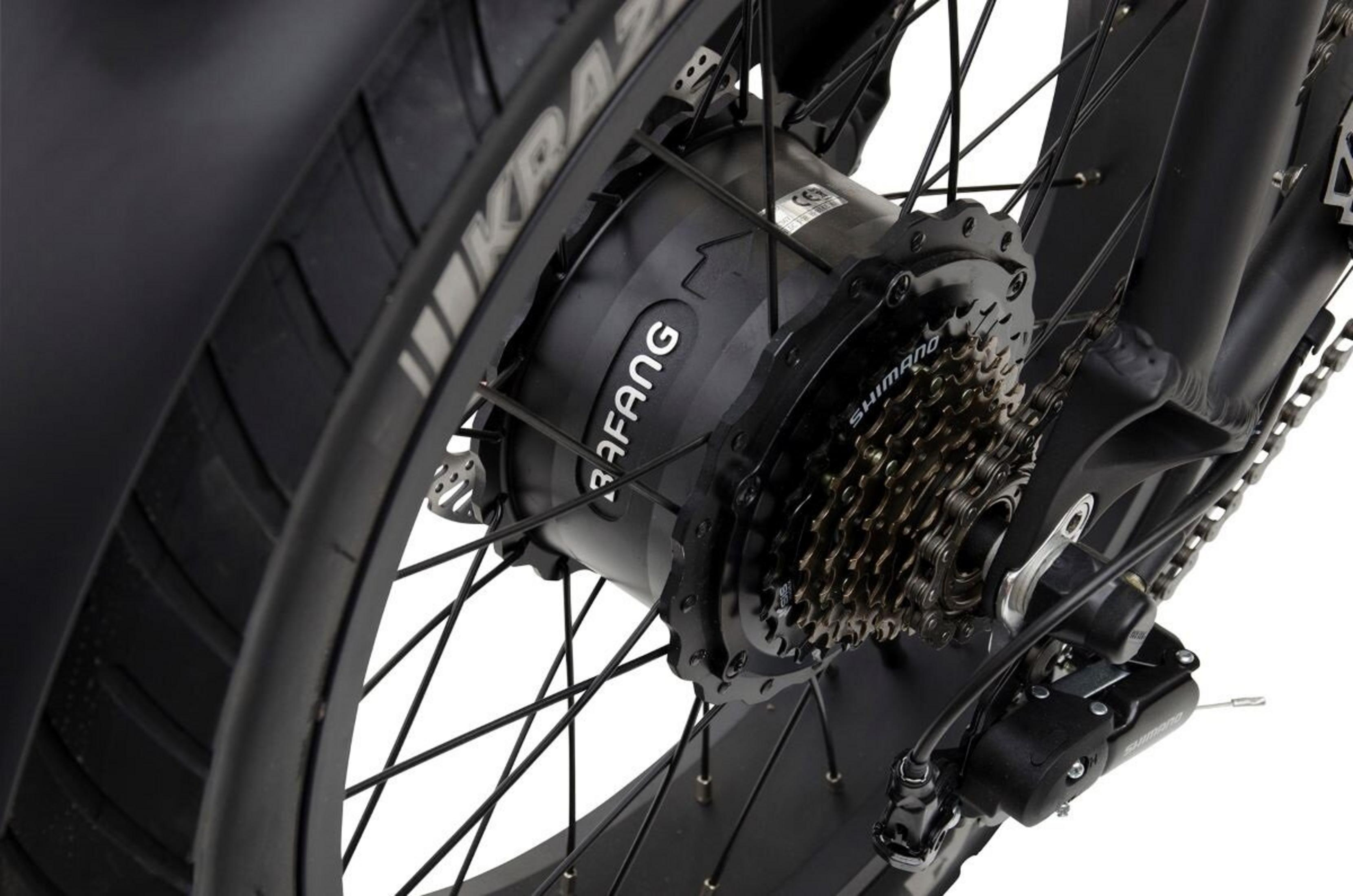 Zbliżenie tylnej piasty roweru elektrycznego, pokazujące silnik Bafang, biegi Shimano i oponę.