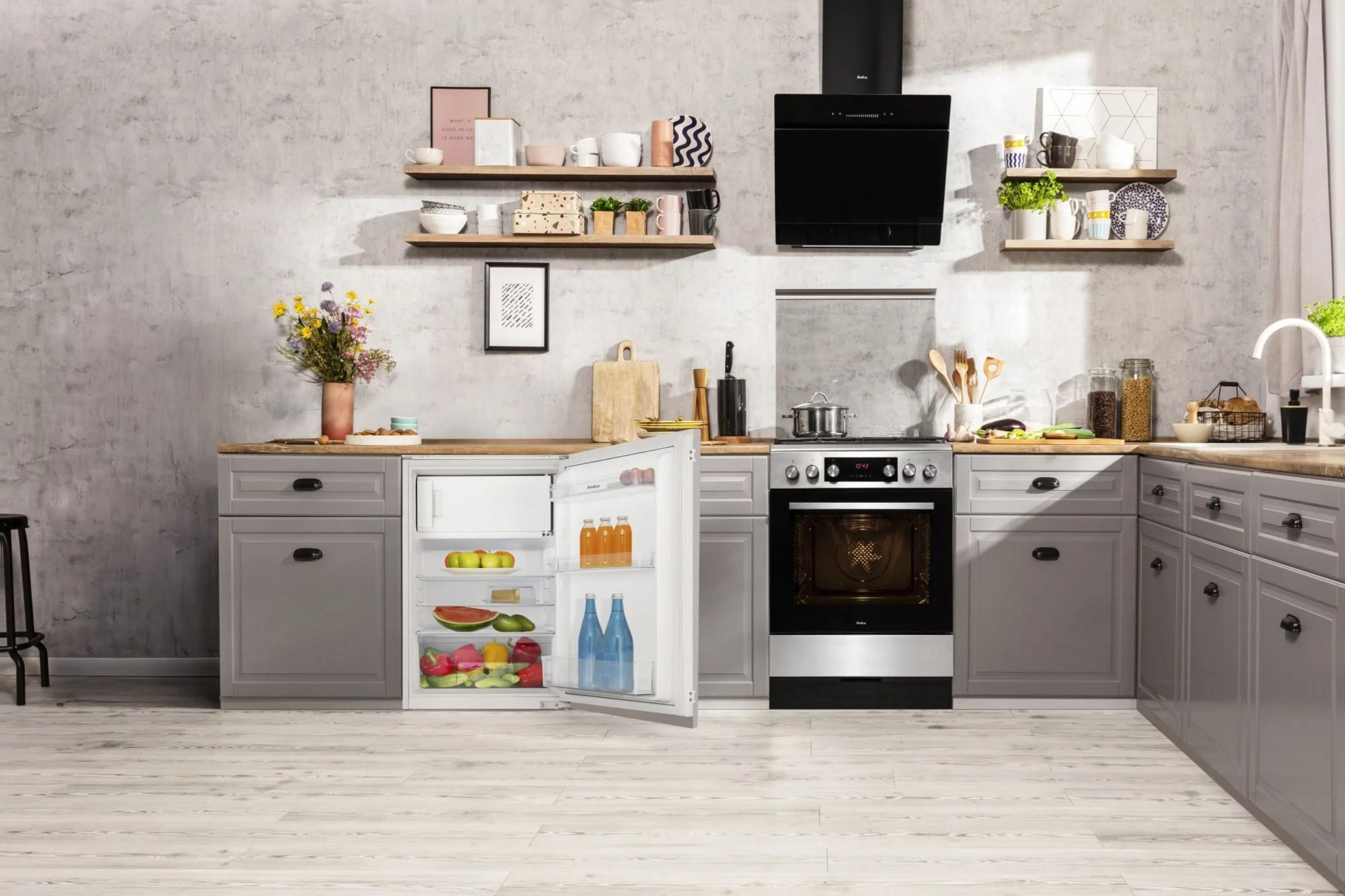 Moderne Küche mit offenem Kühlschrank und Herd. Graue Schränke, Holzarbeitsplatte, Betonwand.