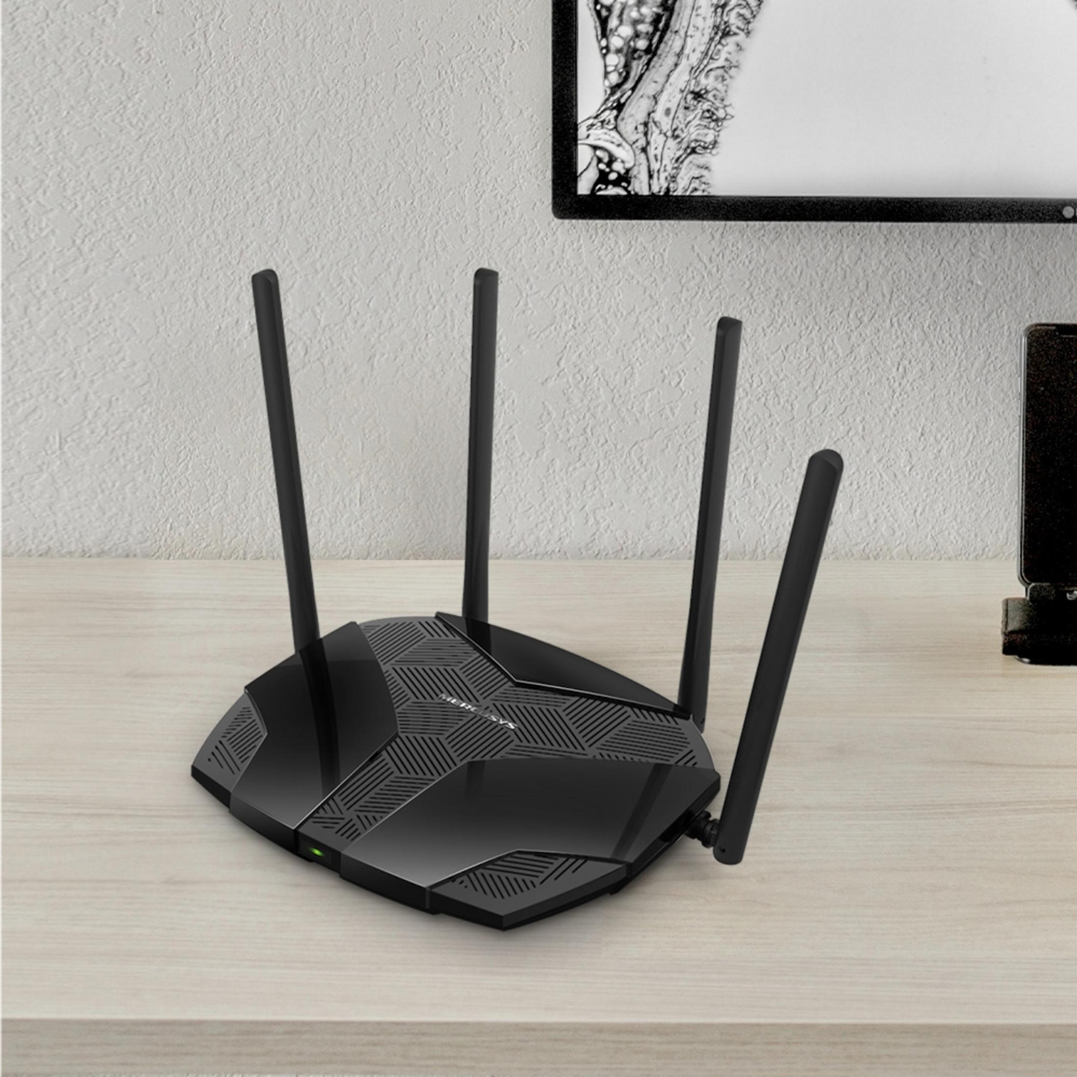 Zwarte router met vier antennes op een houten bureau, met fotolijst en telefoon op de achtergrond.