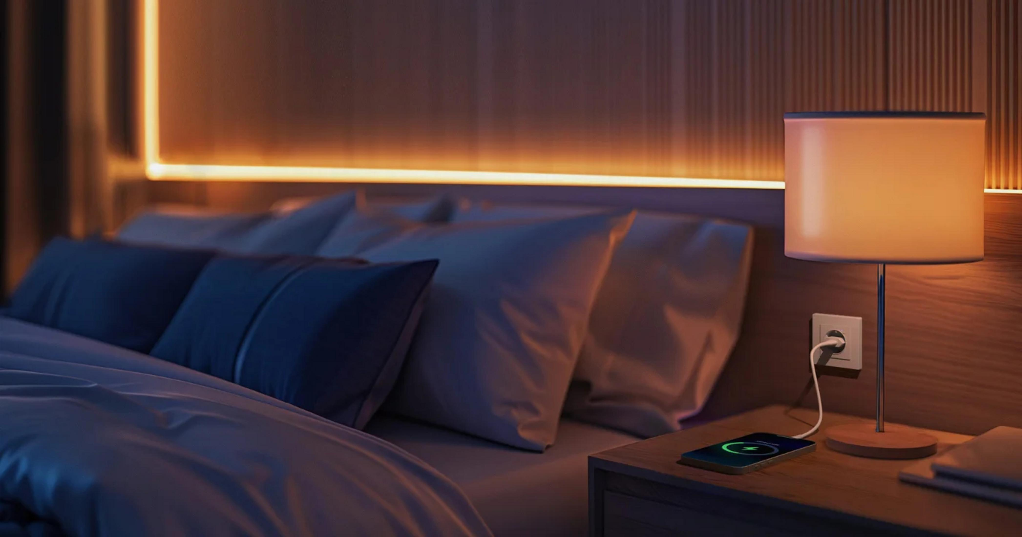 Nachttisch mit Lampe, Handy lädt. Gemütliches Schlafzimmer mit warmer Beleuchtung.