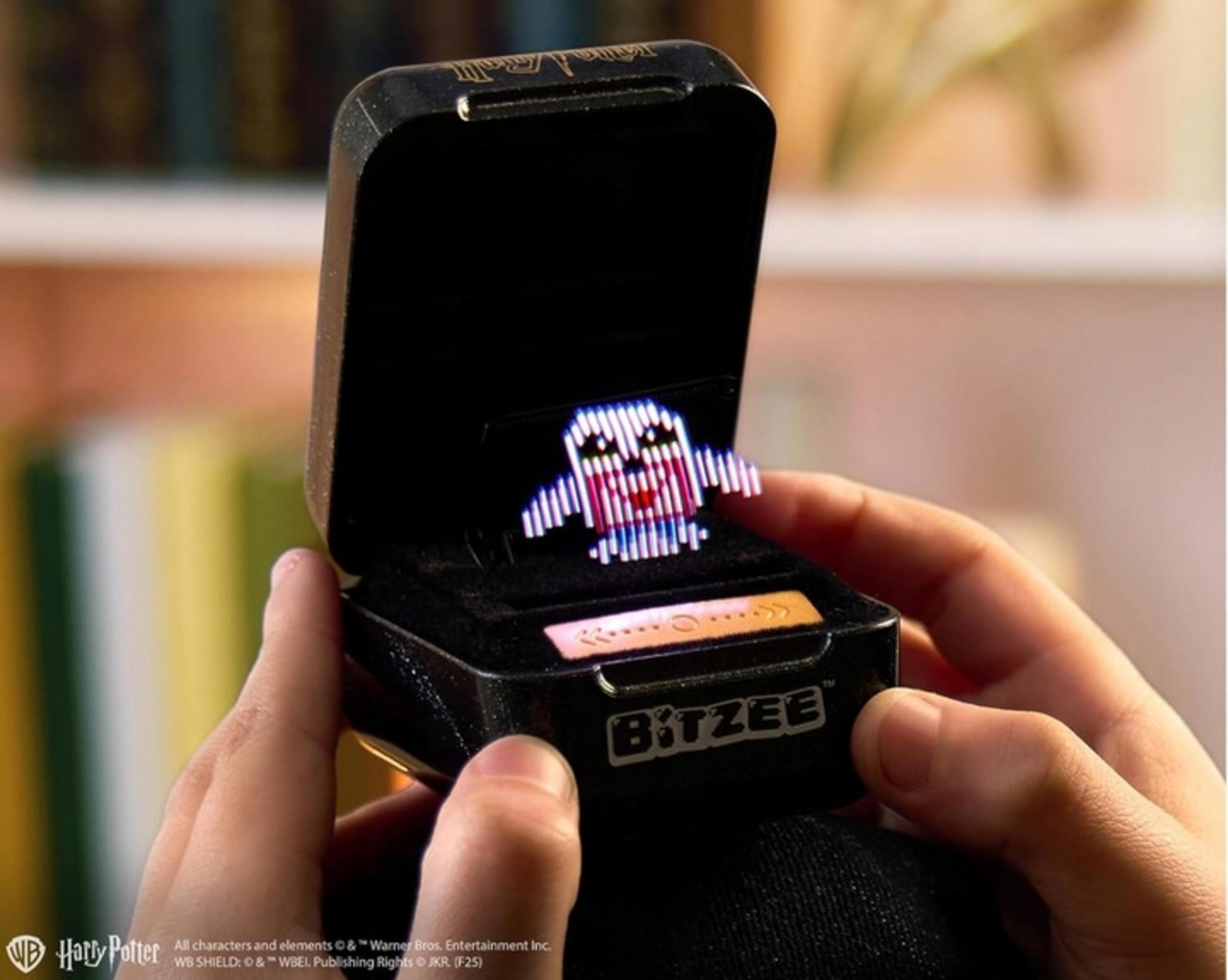 Un juguete Bitzee en un estuche negro con un personaje fantasma pixelado.