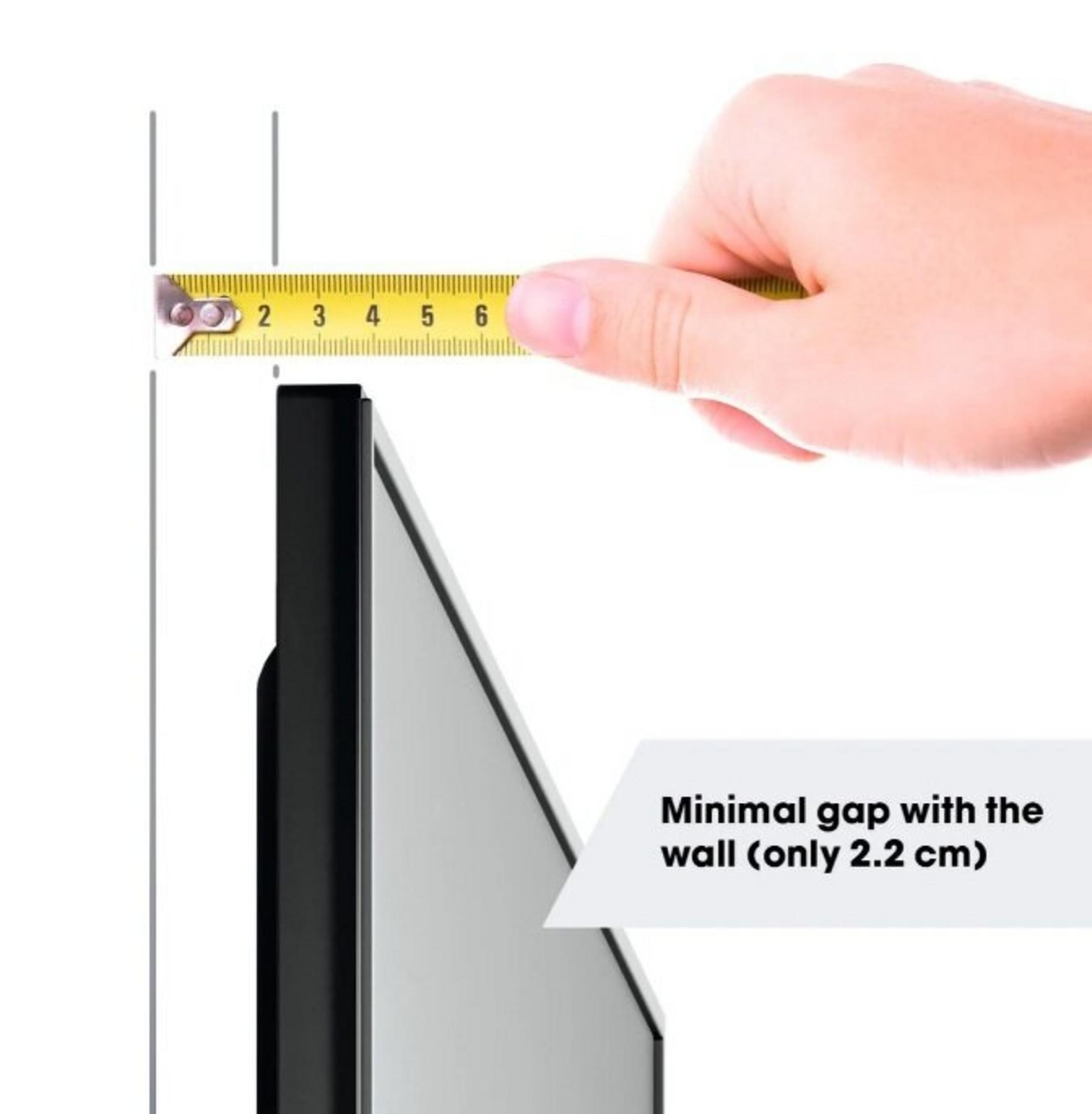 Een hand meet een opening van 2,2 cm met een meetlint naar een zwart apparaat.