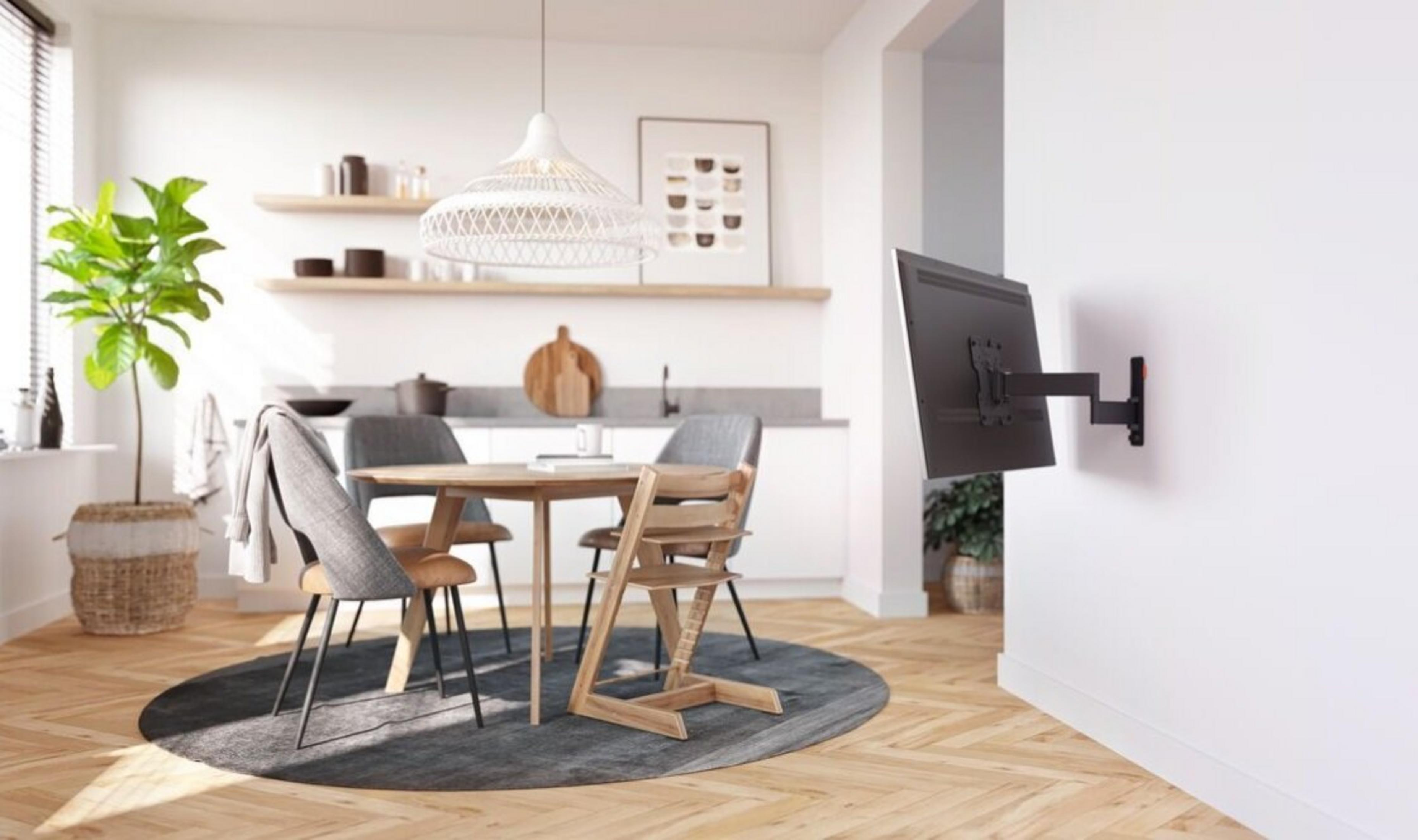 Un comedor moderno con mesa redonda, sillas y un televisor montado en la pared.