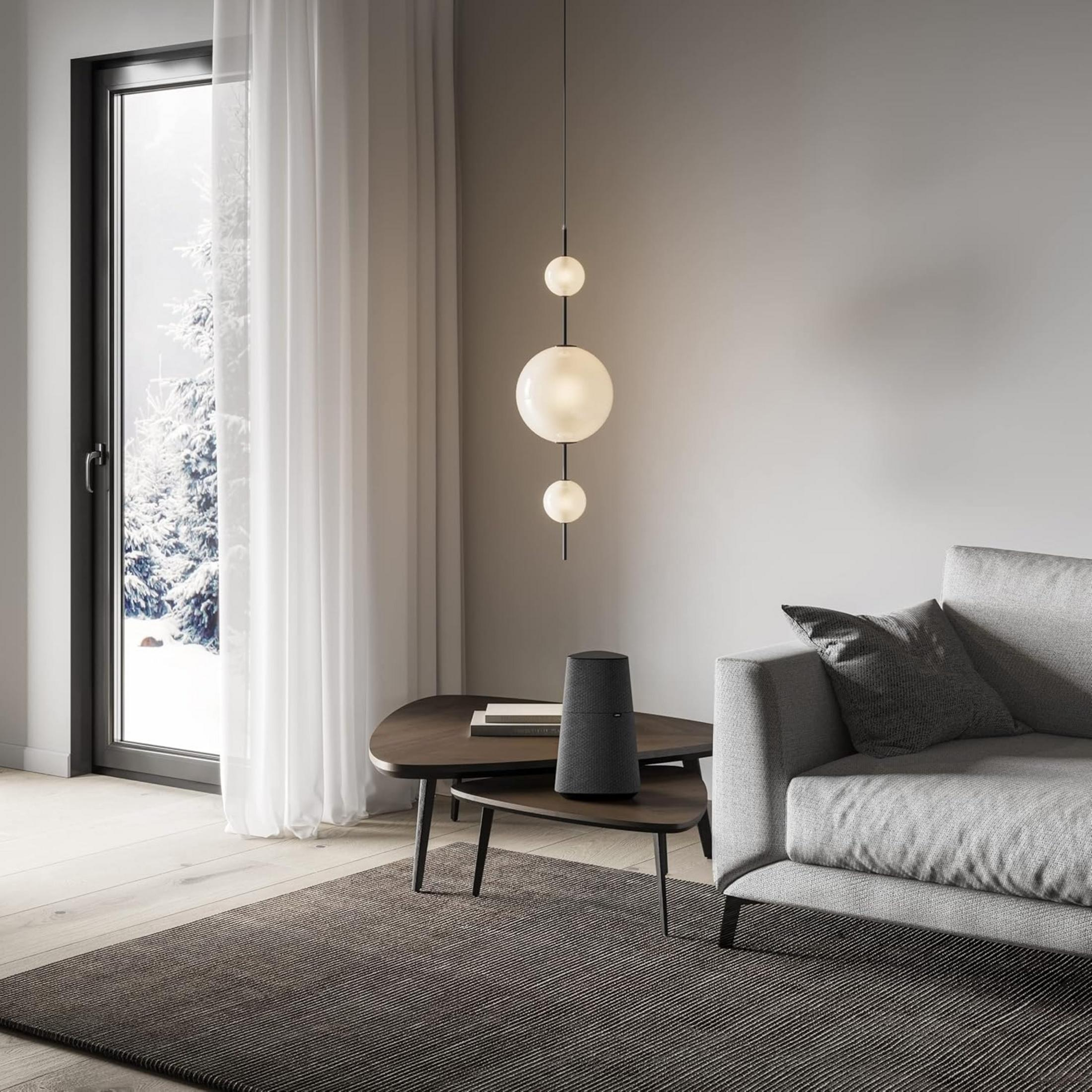 Ein Wohnzimmer mit Sofa, Couchtisch mit Lautsprecher und Fenster mit Schnee.