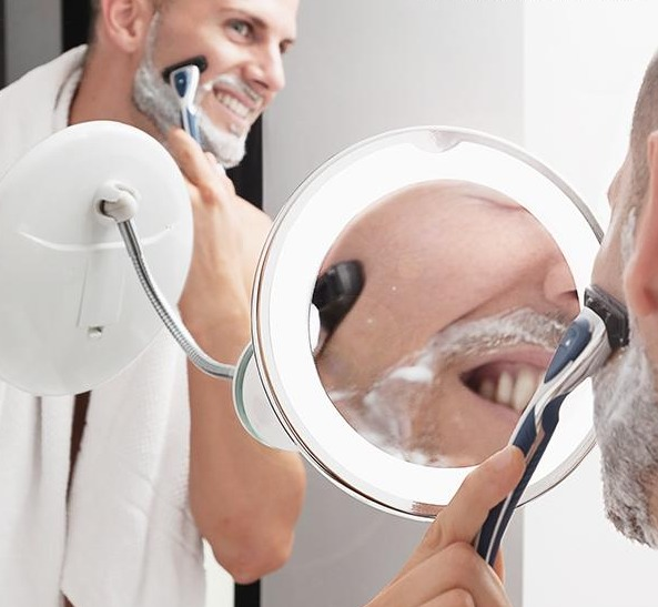 Uomo che si rade allo specchio con schiuma e rasoio.