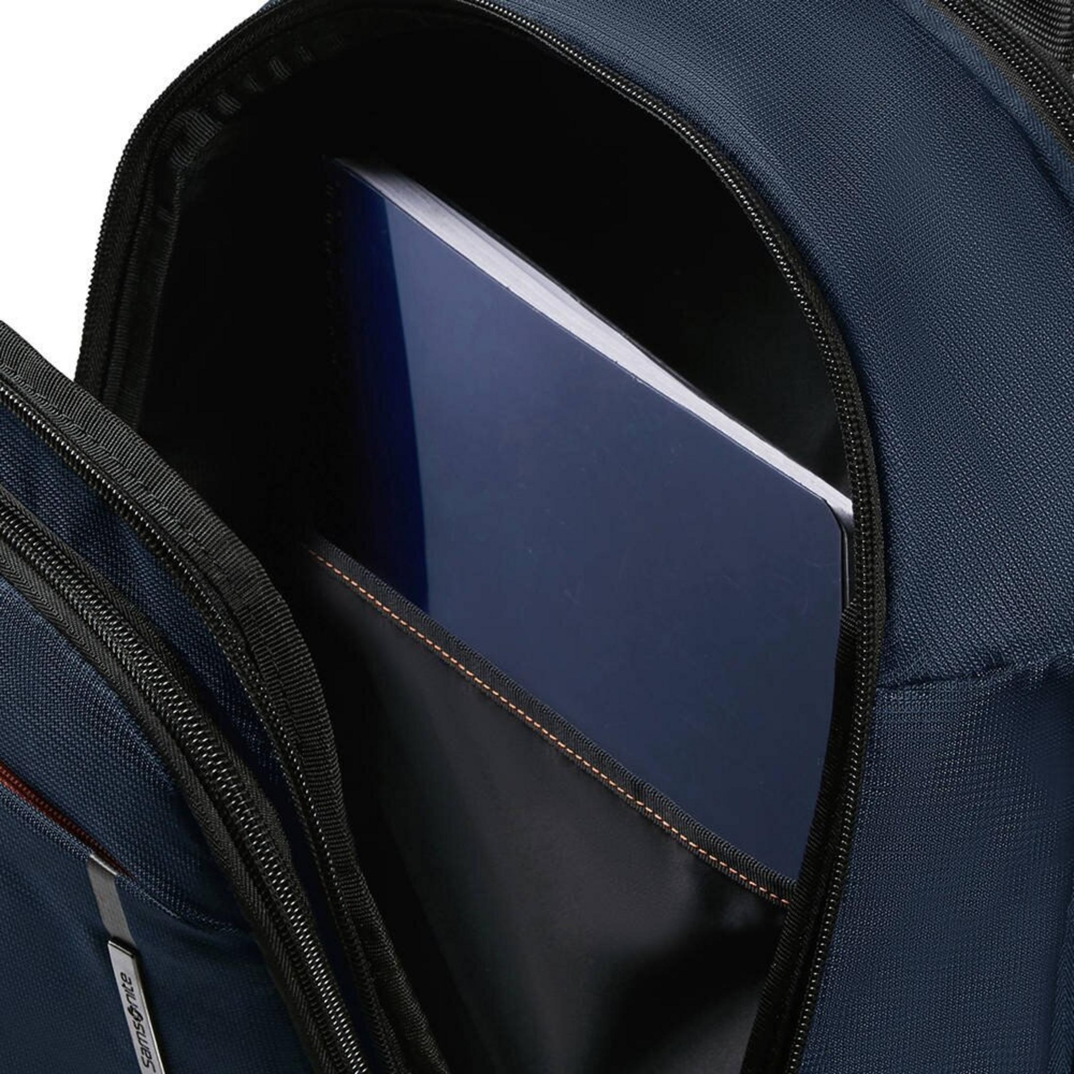 Un cuaderno azul está dentro de un bolsillo abierto de mochila azul oscuro.