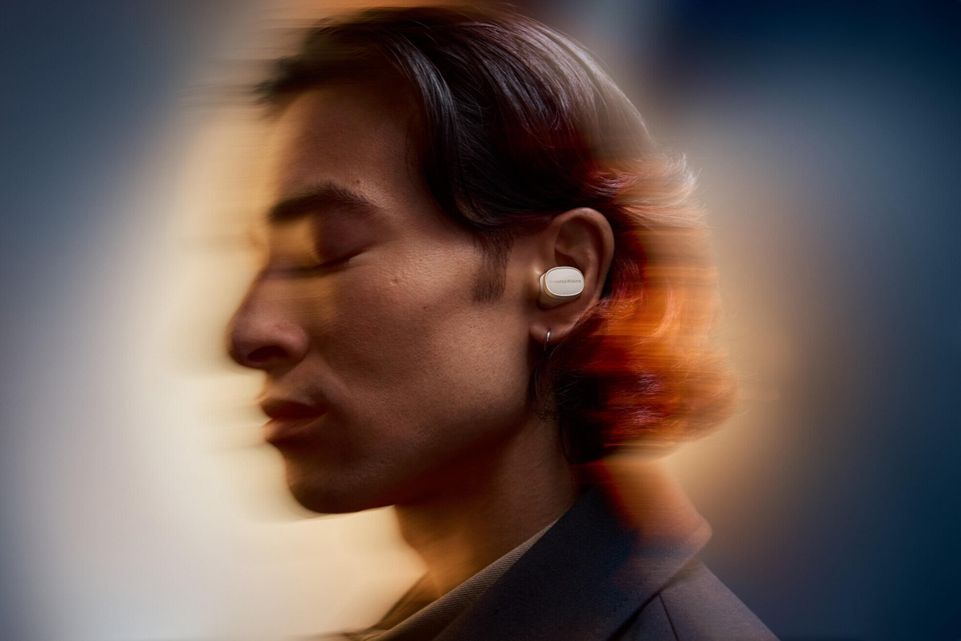 Seitenprofil einer Person mit geschlossenen Augen, die einen weißen Ohrhörer trägt. Bewegungsunschärfe.
