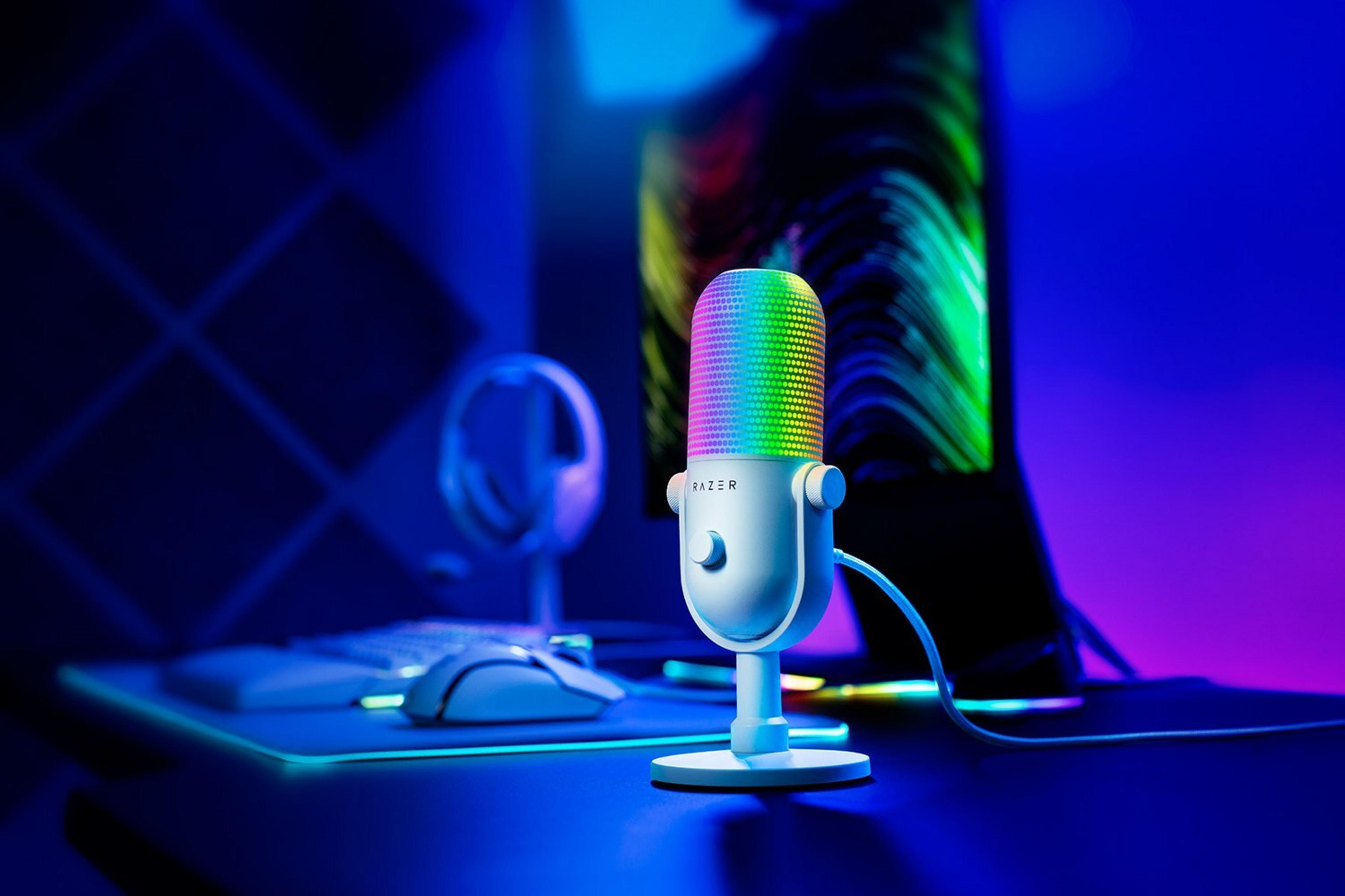 Ein weißes Mikrofon mit RGB-Beleuchtung steht auf einem Schreibtisch neben einer Tastatur und Maus.