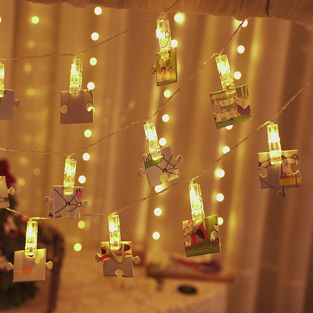 Eine Lichterkette mit angeklipsten Puzzleteilen und Zeichentrickfiguren, beleuchtet von warmen LEDs.