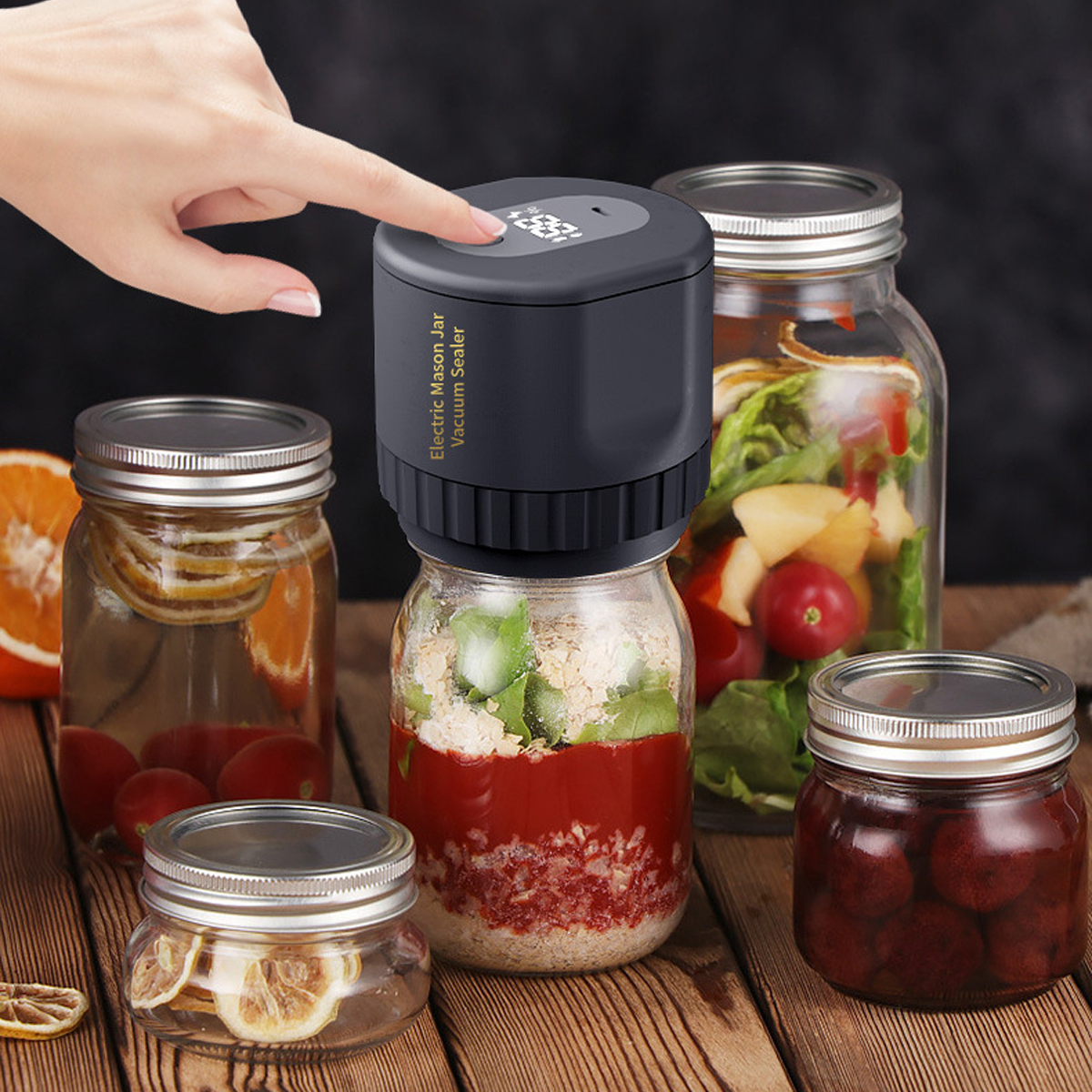 Eine Hand drückt einen Vakuumversiegler auf ein mit Essen gefülltes Glas. Andere Gläser mit Essen sind drumherum.