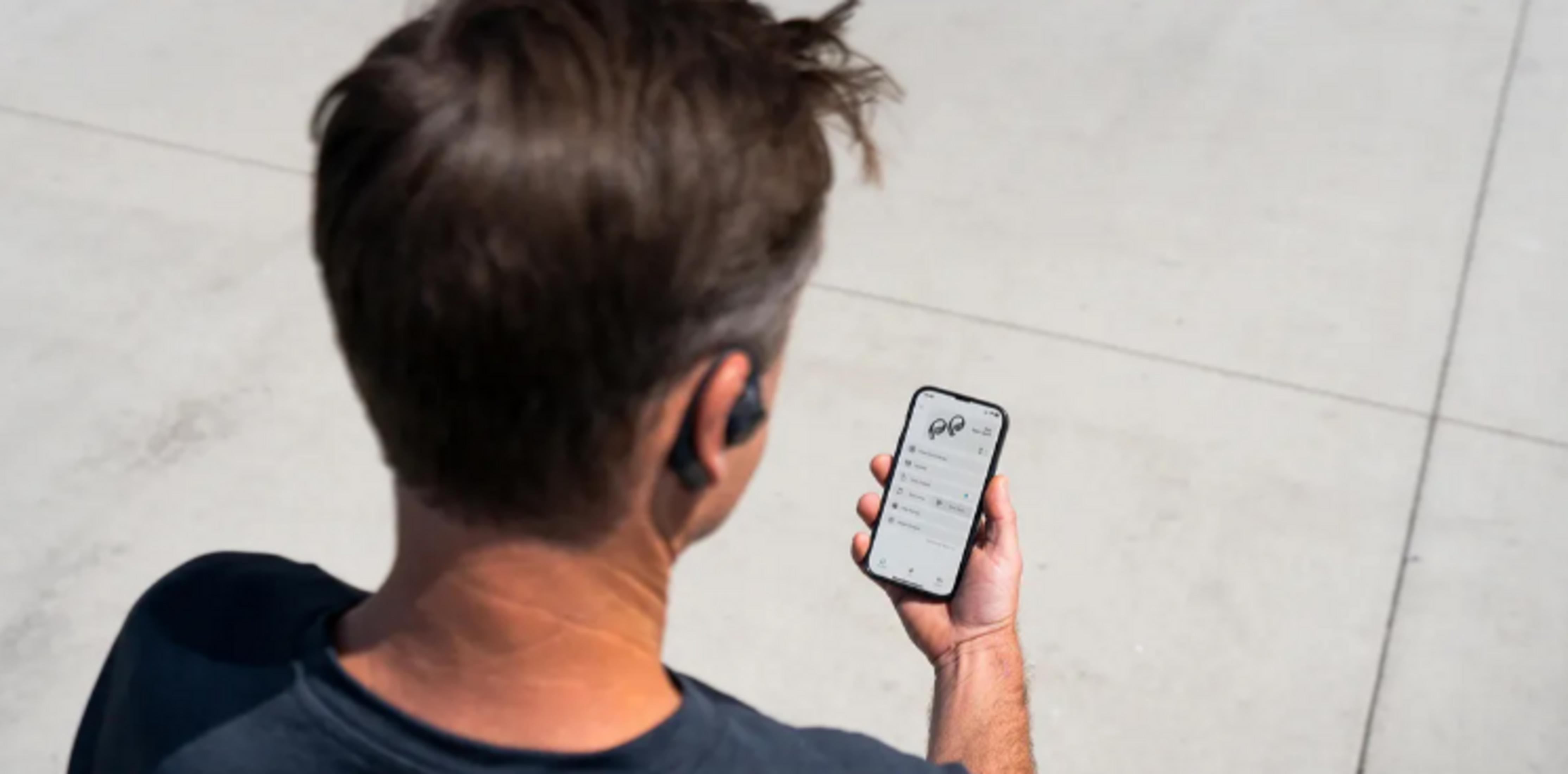 Uomo con auricolari usa telefono, mostra app con icone auricolari e stato batteria.