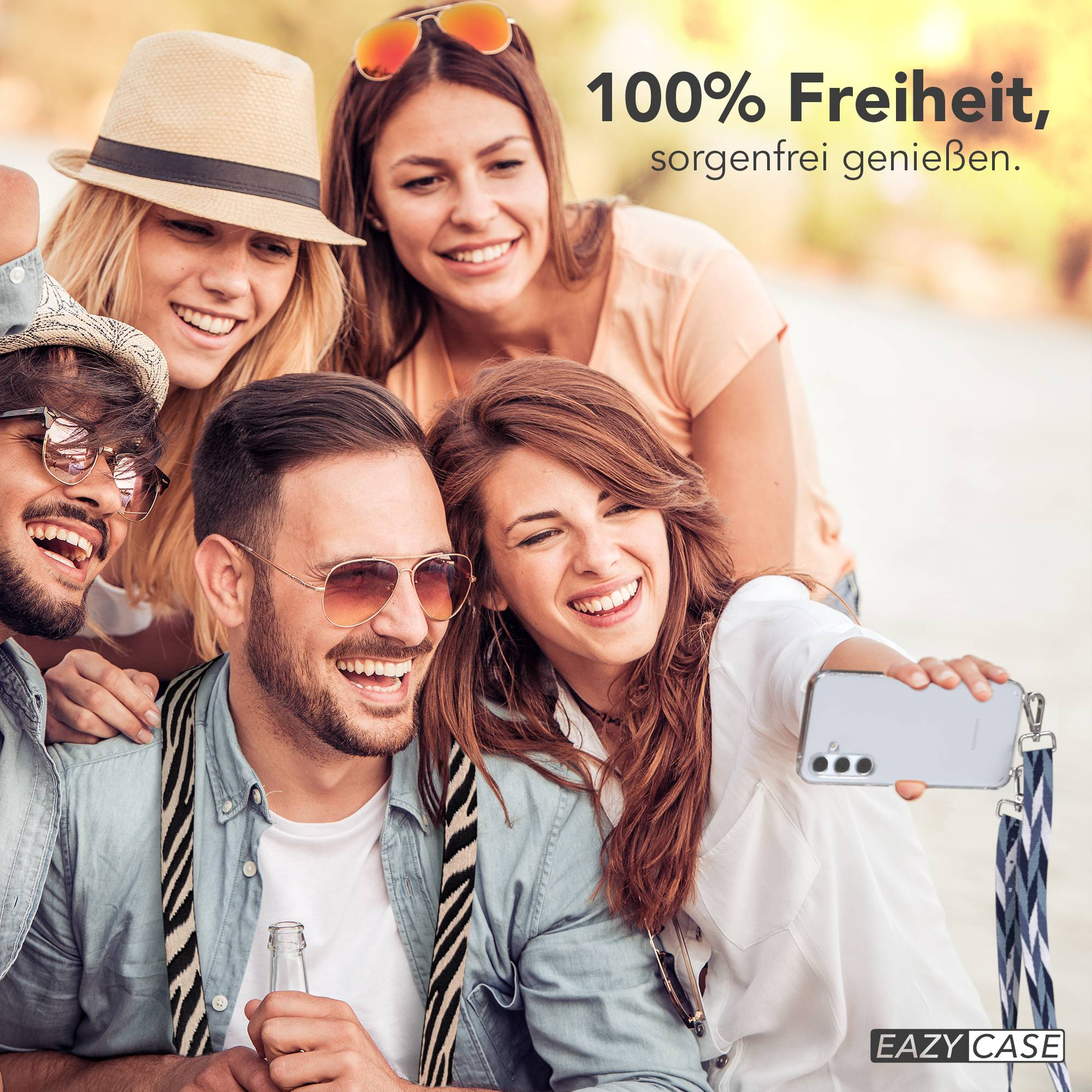 Vier lächelnde Freunde machen draußen ein Selfie. Einer hält ein Handy, ein anderer eine Flasche.