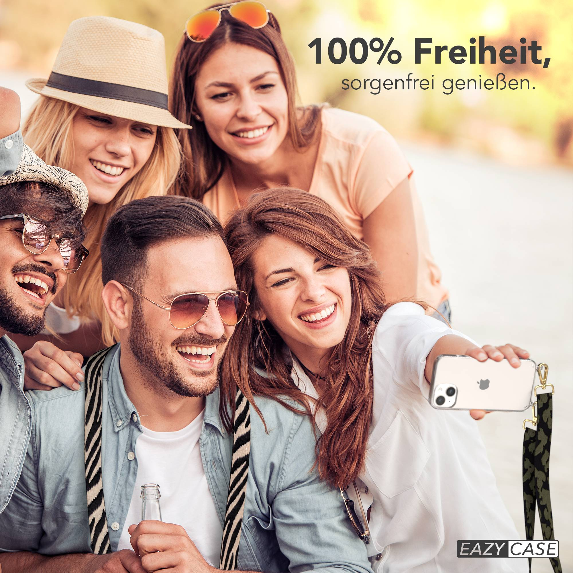 Vier lächelnde Freunde machen ein Selfie im Freien. Einer hält ein Handy und eine Flasche.