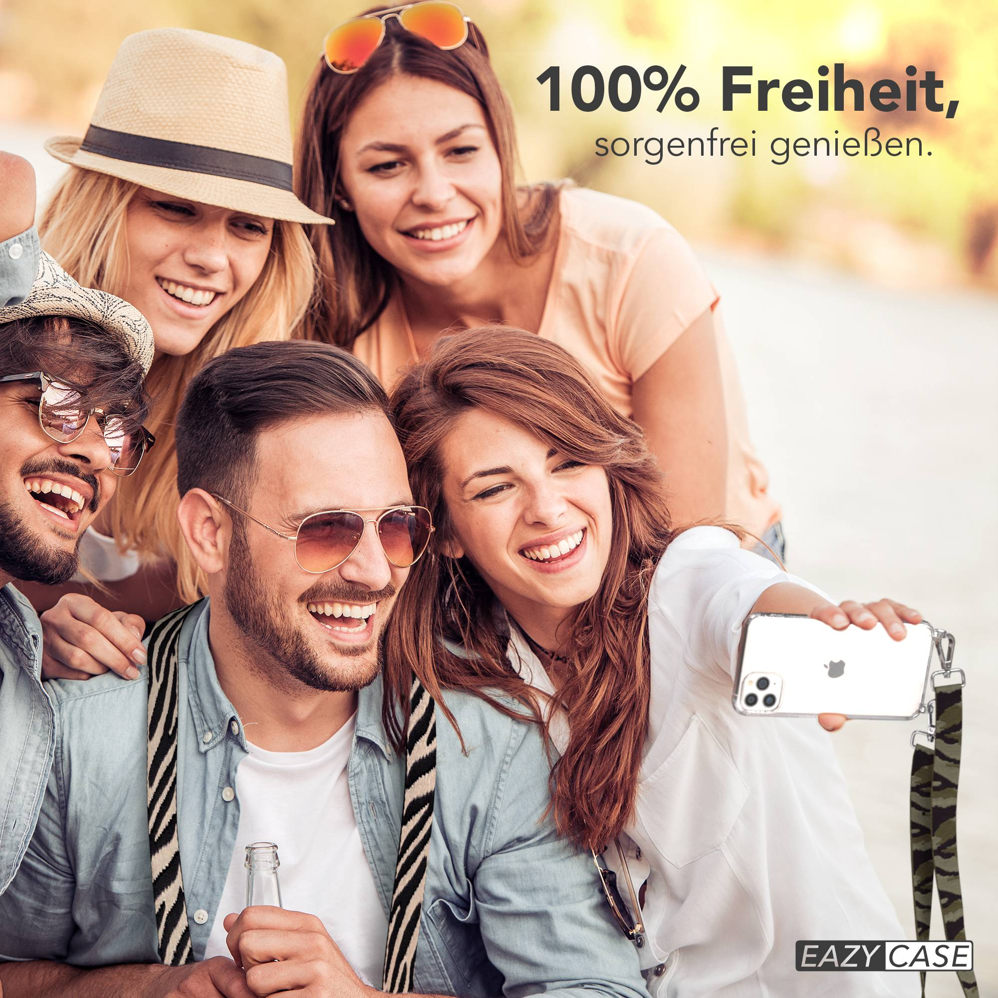 Vier lachende Freunde machen ein Selfie im Freien, eine Frau hält das Handy.