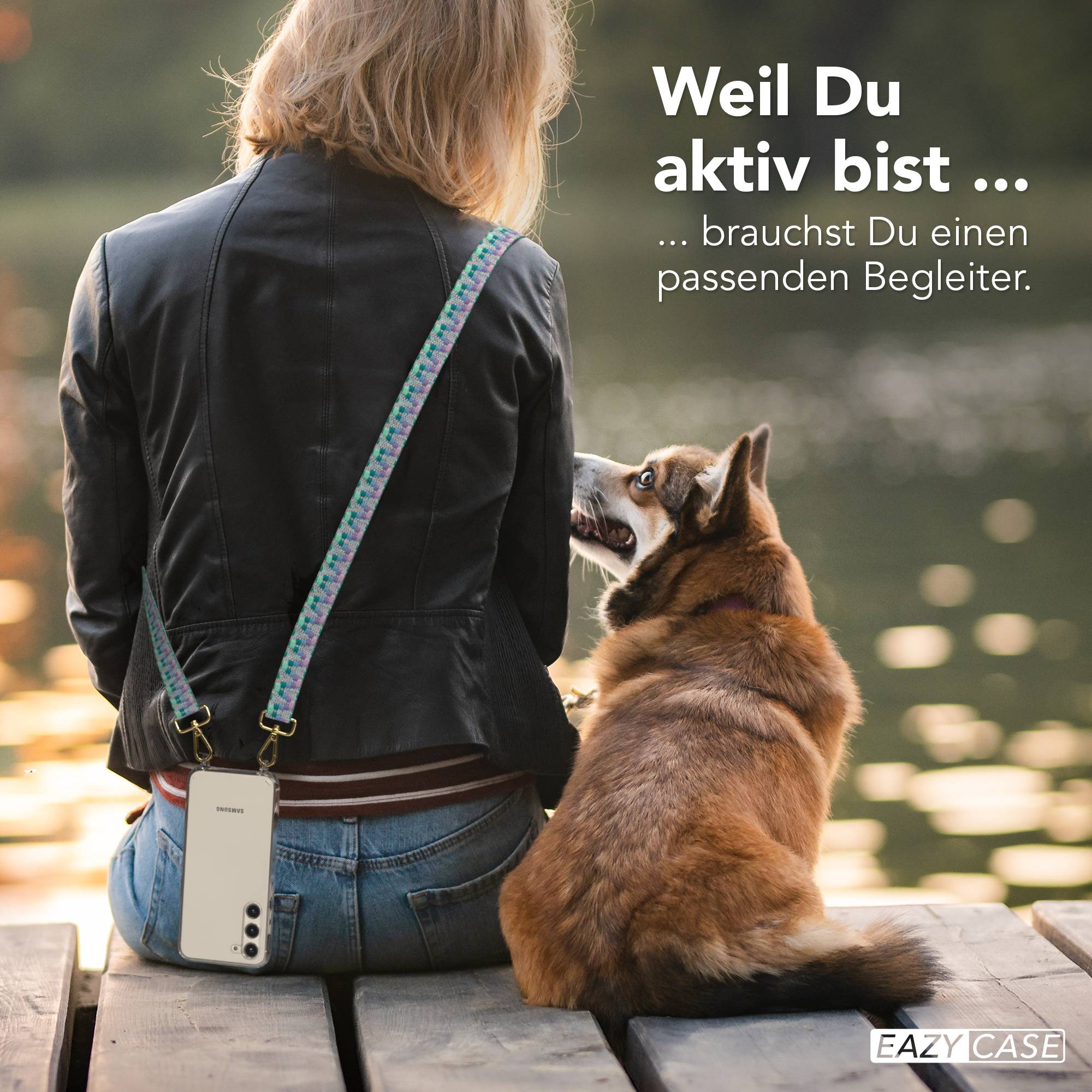 Frau in Lederjacke mit Handy am Gurt sitzt auf Steg mit Hund, der hochschaut.