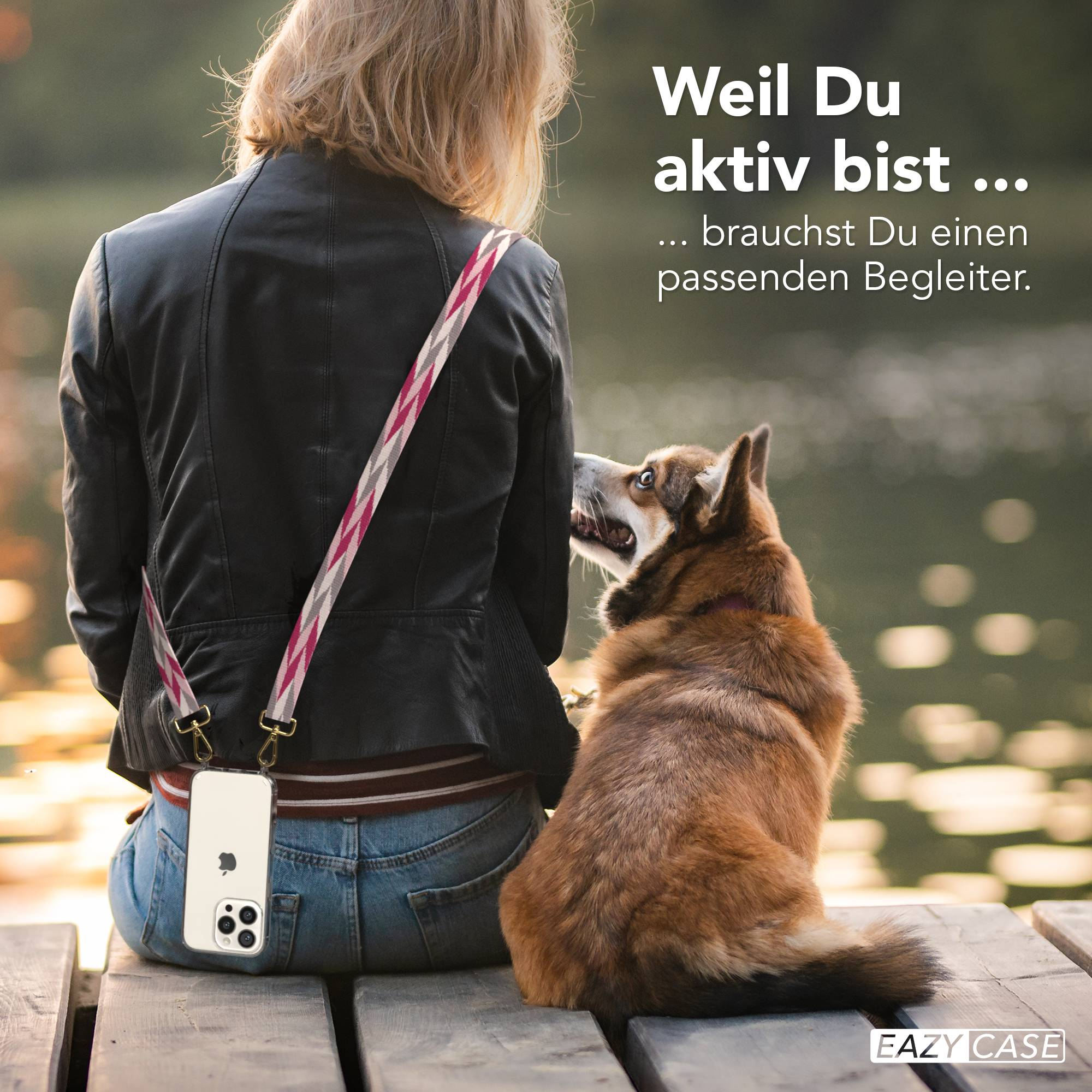 Ein Hund sitzt neben einer Person, die eine Handyhülle trägt.