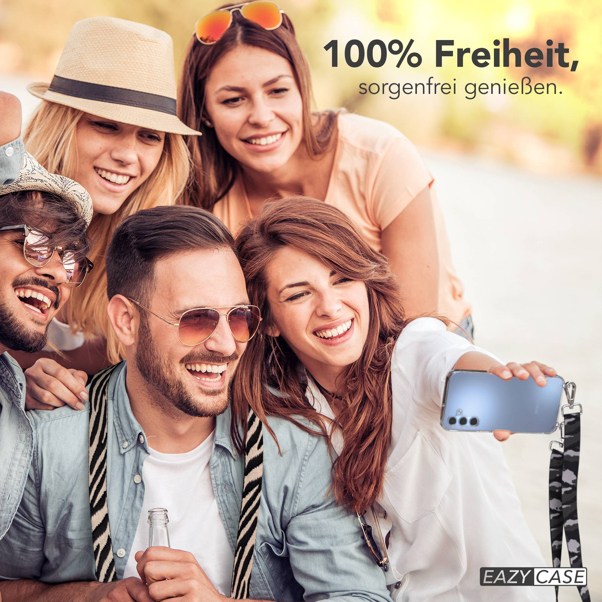 Vier lachende Freunde machen draußen ein Selfie mit einem Handy. Text: 100% Freiheit, sorgenfrei genießen.