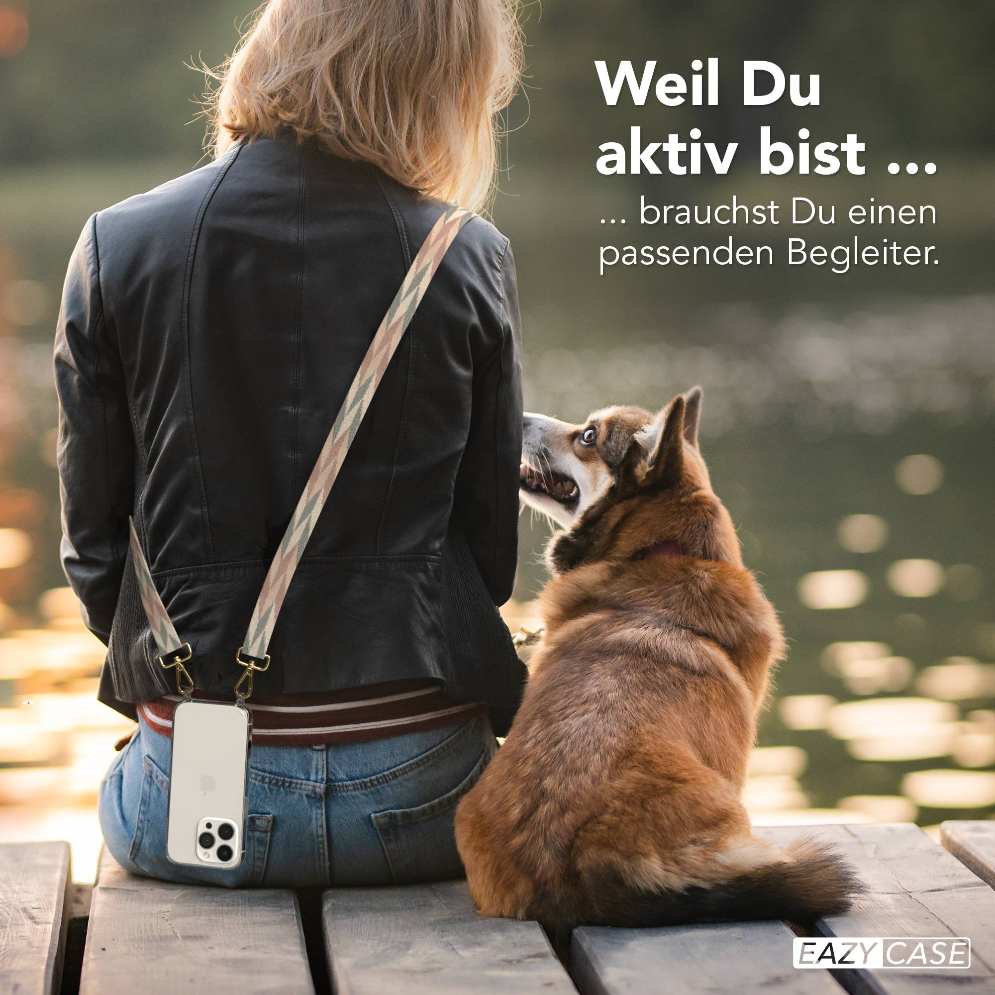 Frau mit Hund sitzt auf Holzsteg, Handy mit Trageband.