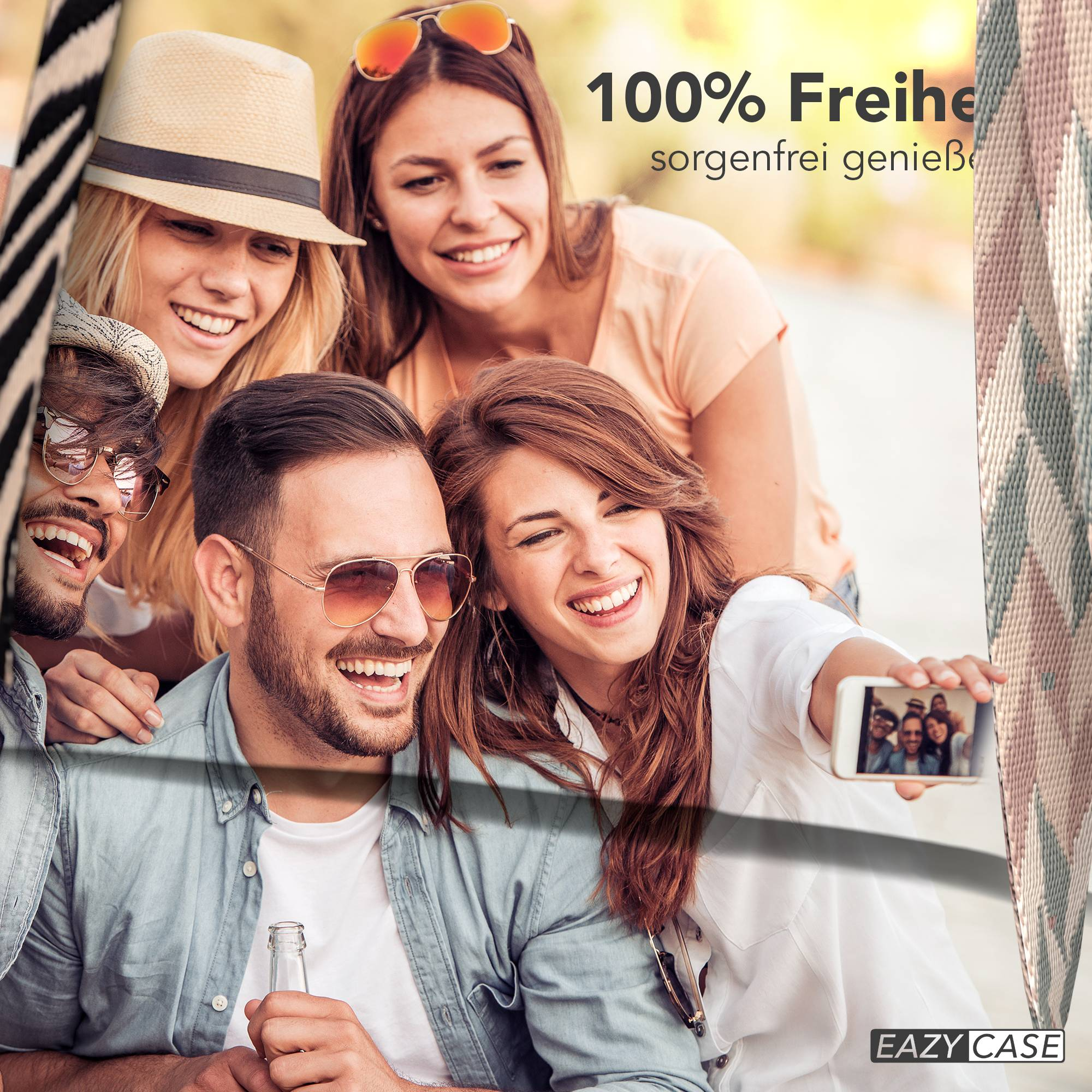 Vier lachende Freunde machen draußen ein Selfie, einer hält ein Handy, der andere eine Flasche.