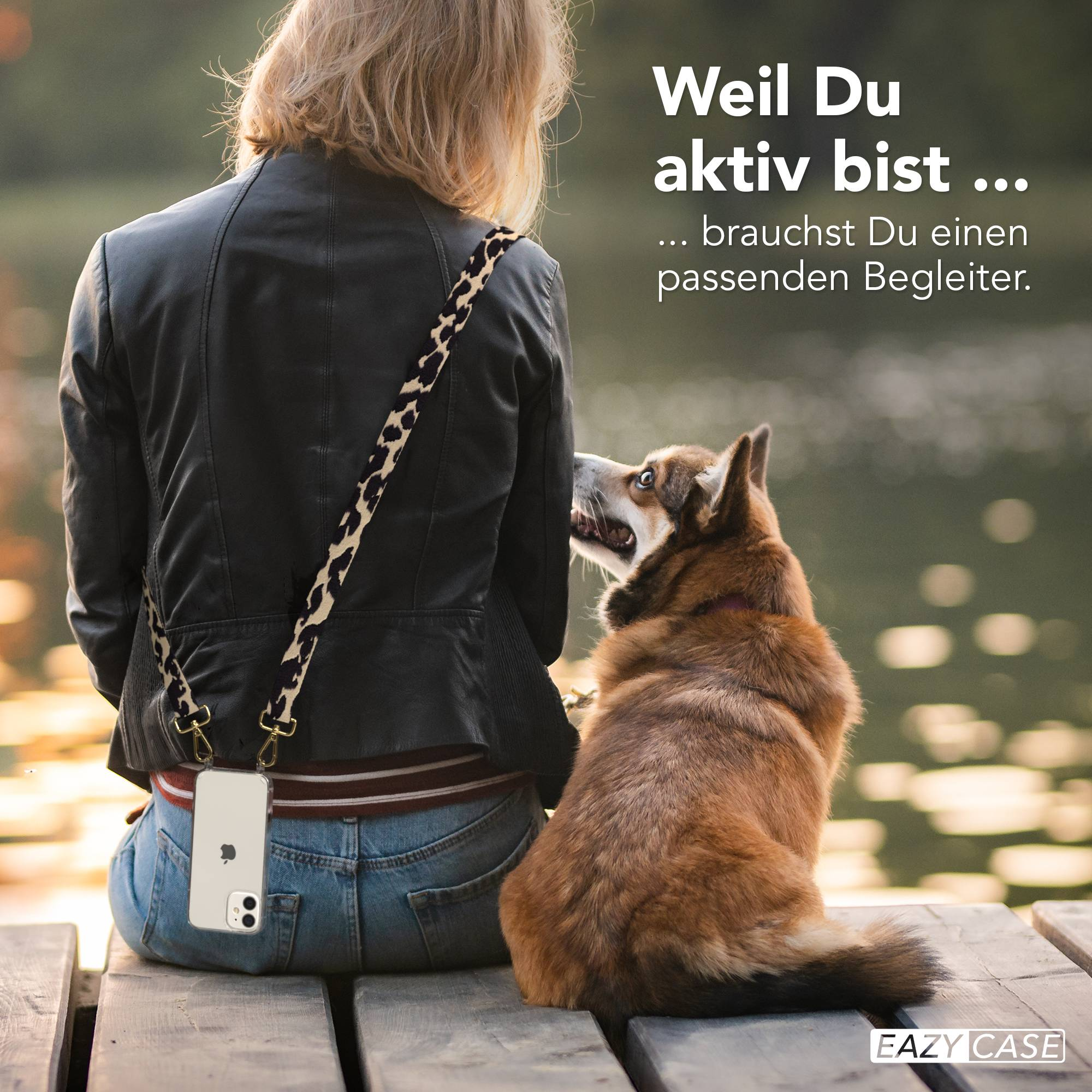 Frau mit Hund sitzt auf Holzsteg, Handy mit Leo-Muster-Gurt.