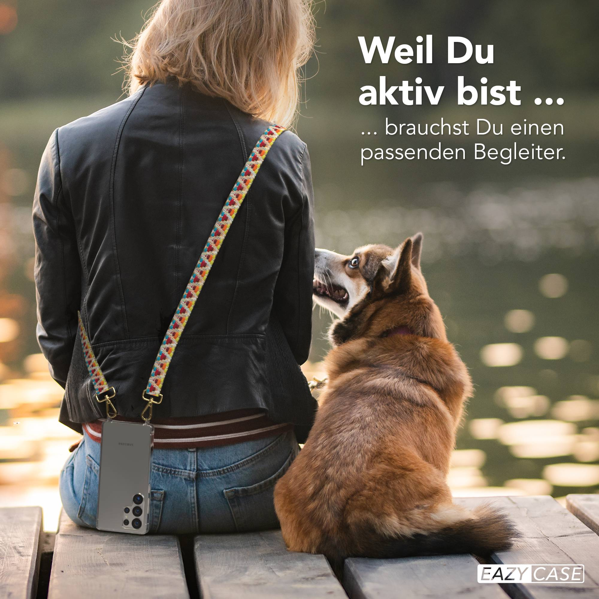 Eine Frau mit Hund sitzt auf einer Holzplanke. Ein Handy ist an ihr befestigt.