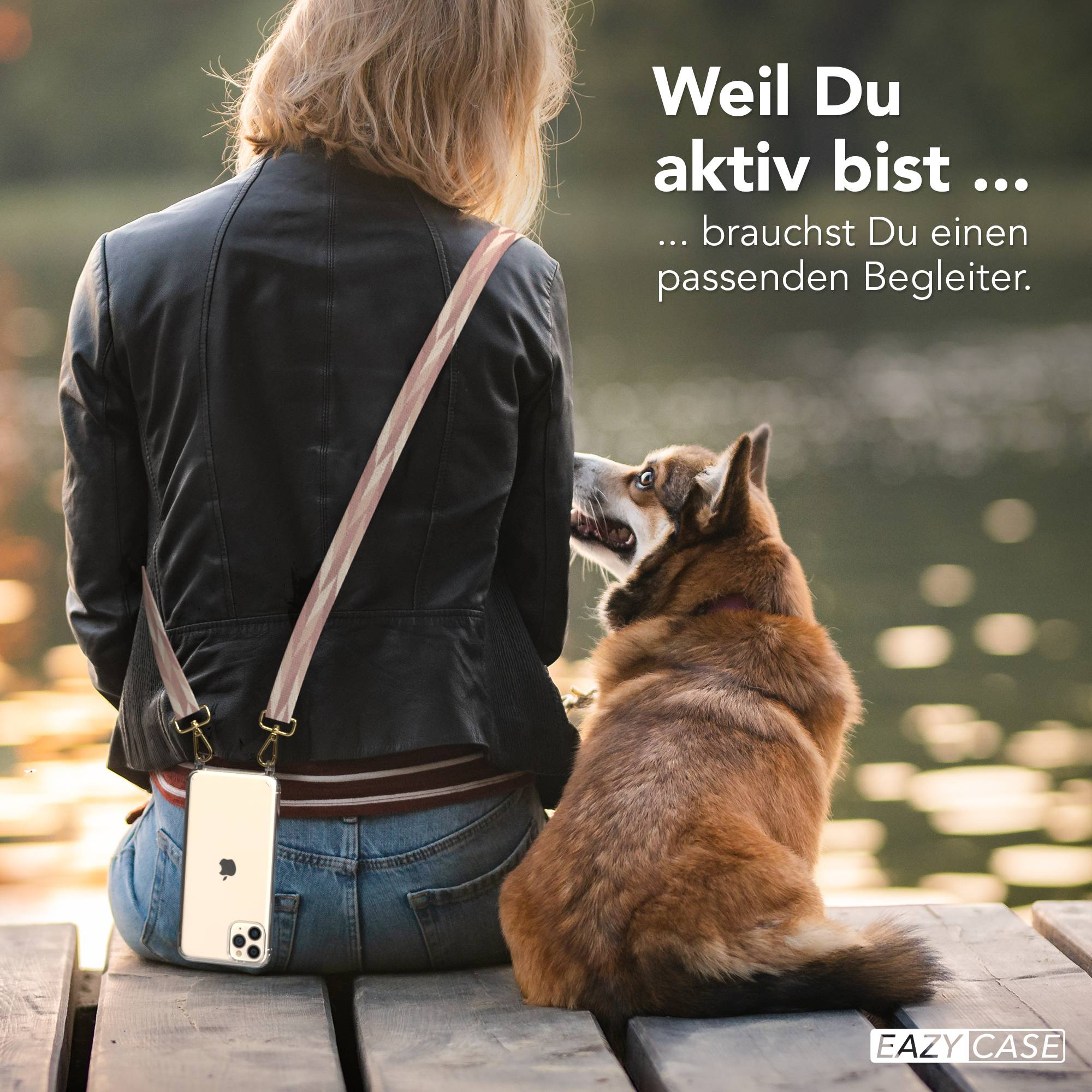 Frau mit Hund sitzt auf Holzsteg, Handy umgehängt. Wasser im Hintergrund.