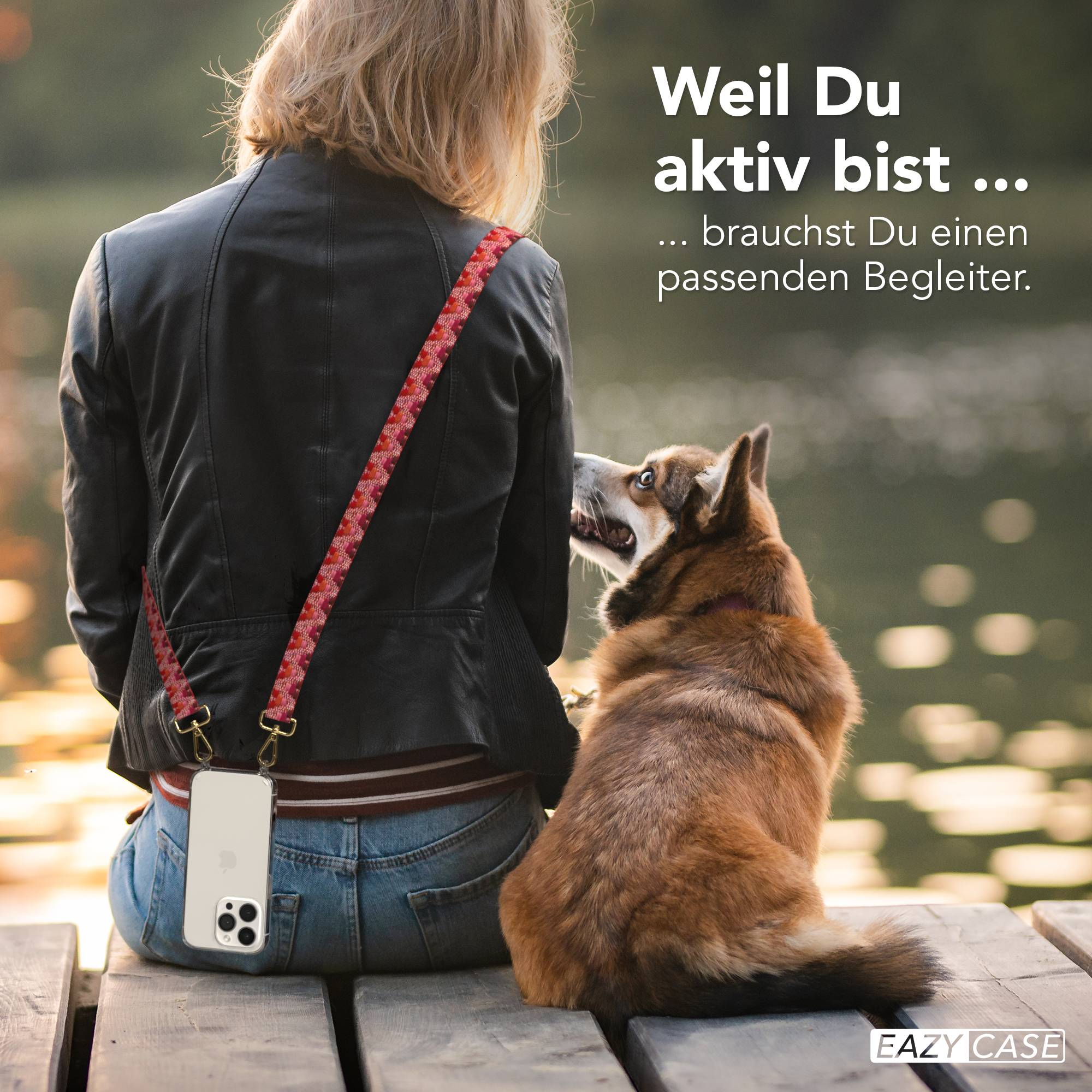 Eine Frau mit einem Hund sitzt auf einer Holzbank am Wasser.