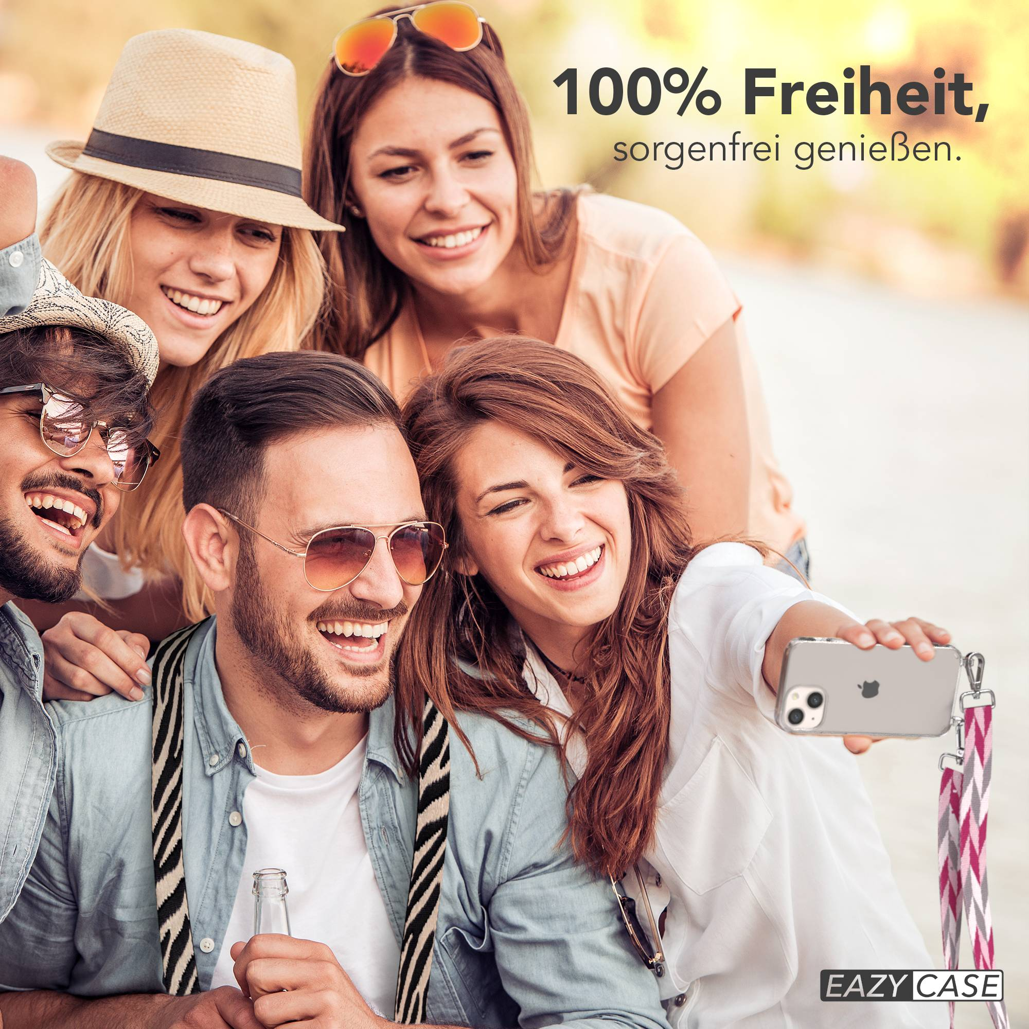 Vier Freunde machen ein Selfie im Freien, eine Frau hält ein Handy und lacht.