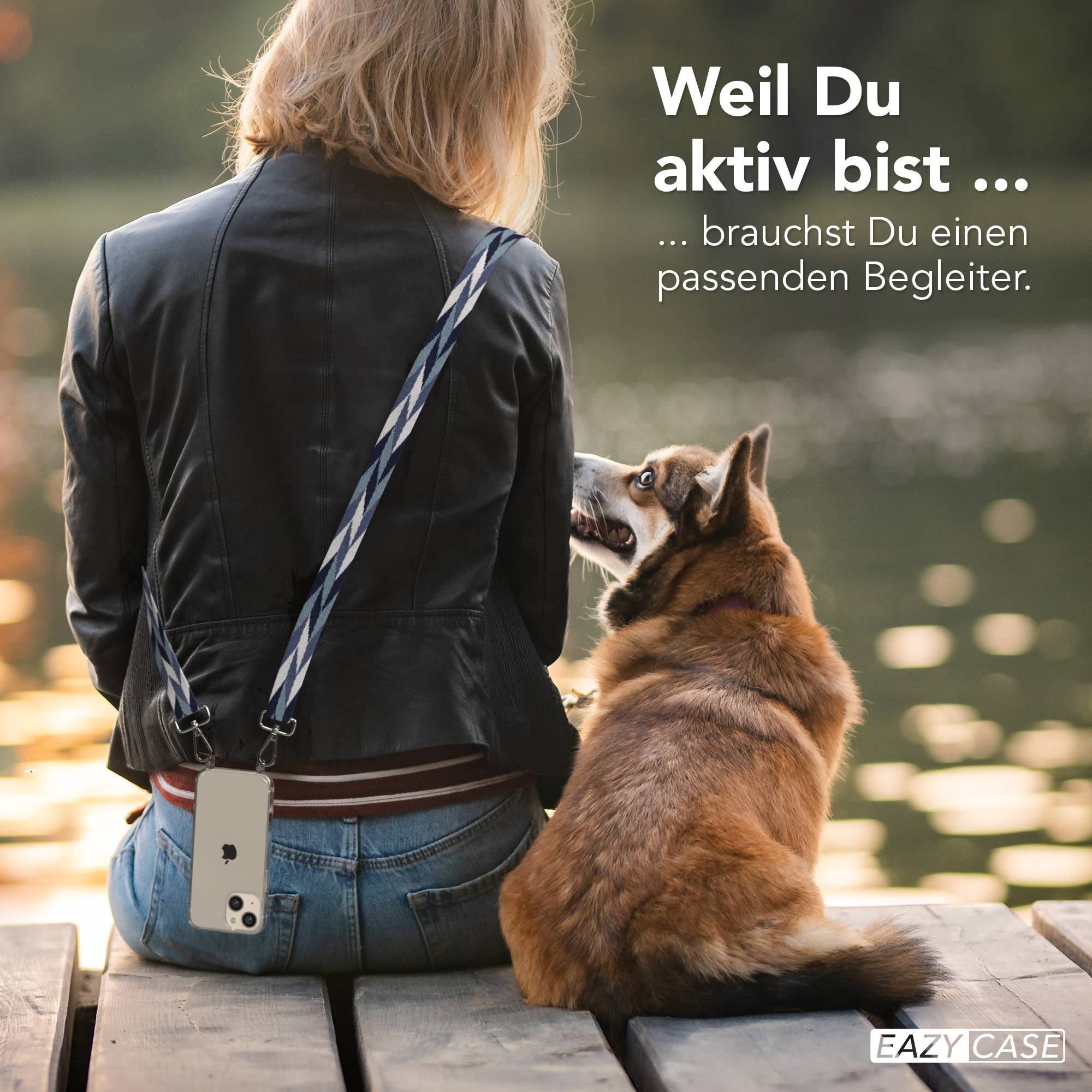 Frau mit Hund sitzt auf Holzsteg am Wasser. Handy am Trageriemen.