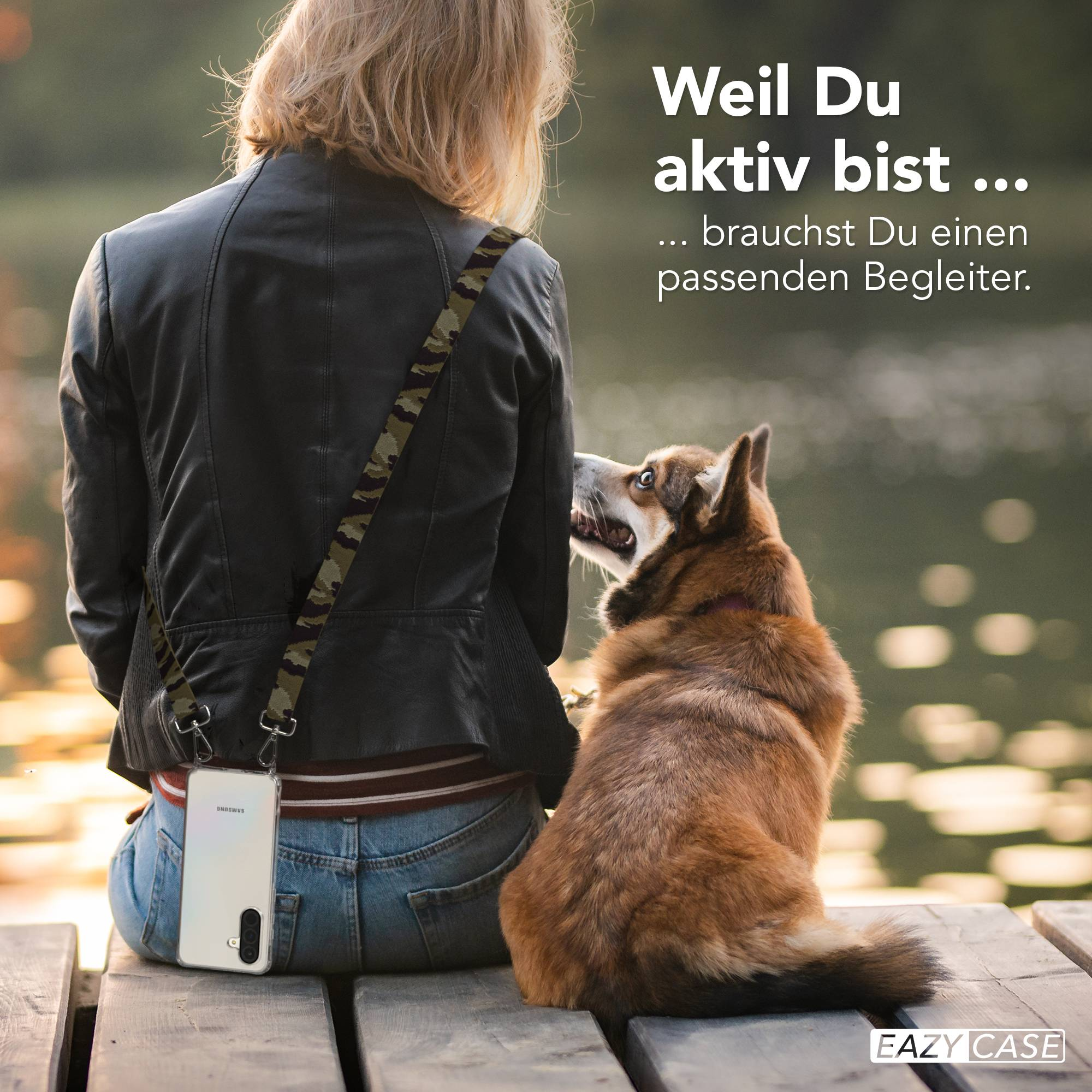 Frau mit Hund sitzt auf einer Holzbank, Handy mit Trageband.