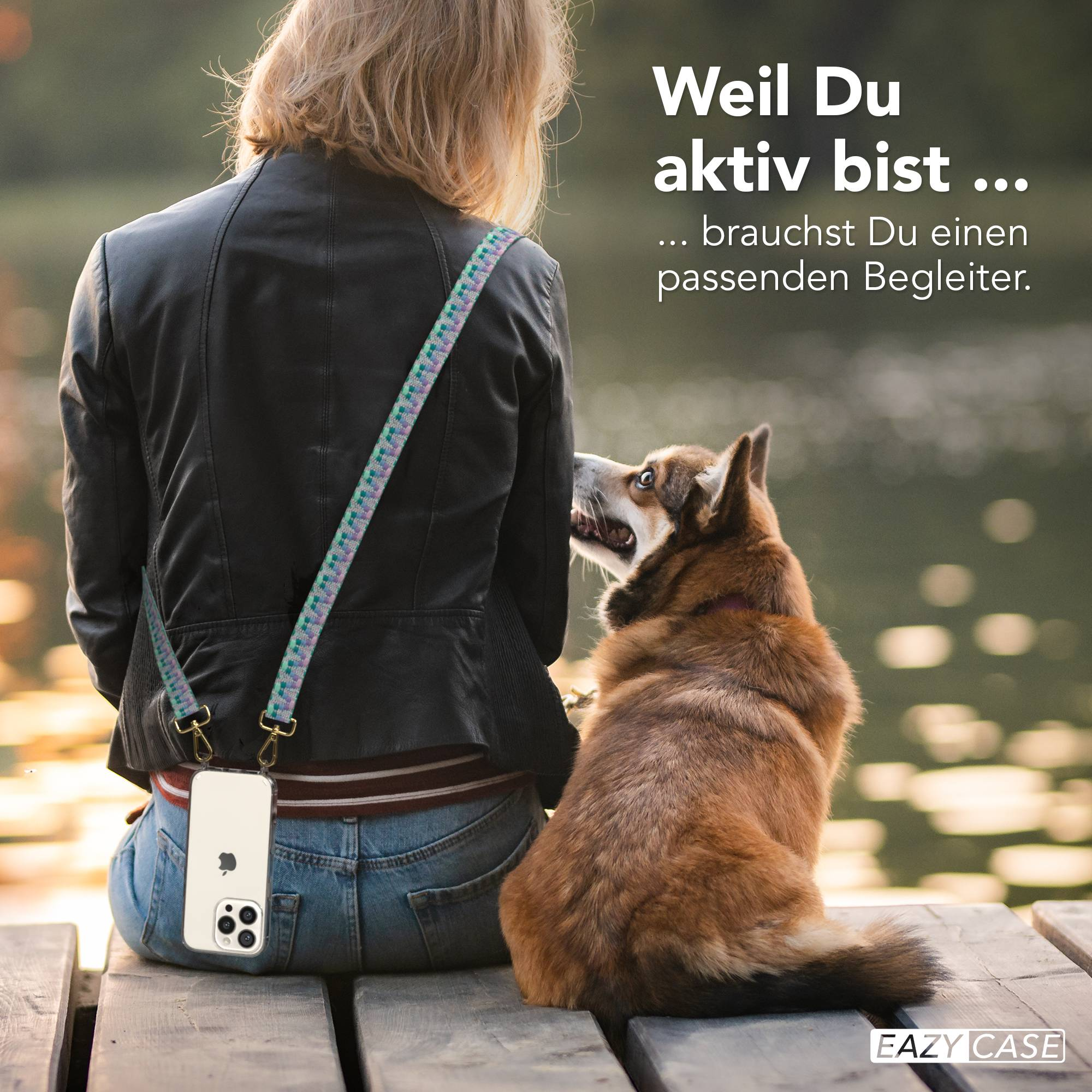 Frau mit Hund sitzt auf Holzsteg, Handy mit Tragegurt.