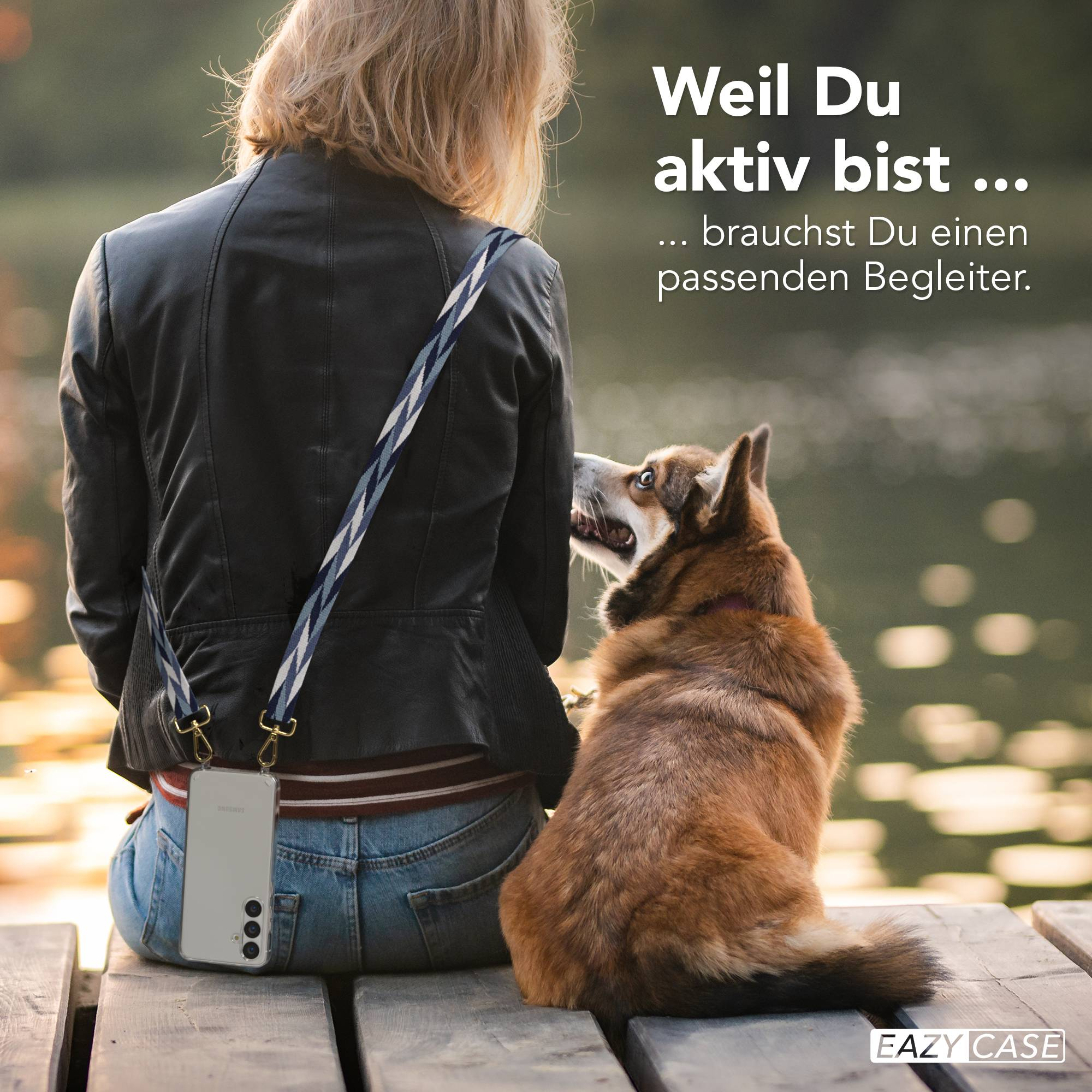 Eine Person in Lederjacke und Jeans sitzt auf einem Holzsteg, ein Hund schaut zu ihr auf.