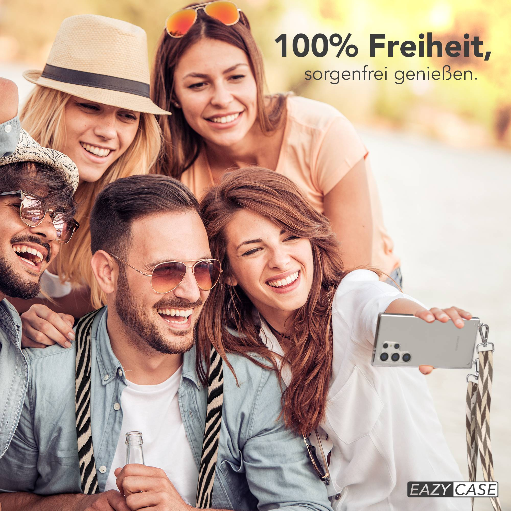 Fünf lachende Freunde machen ein Selfie bei Sonnenschein, eine Frau hält das Handy.