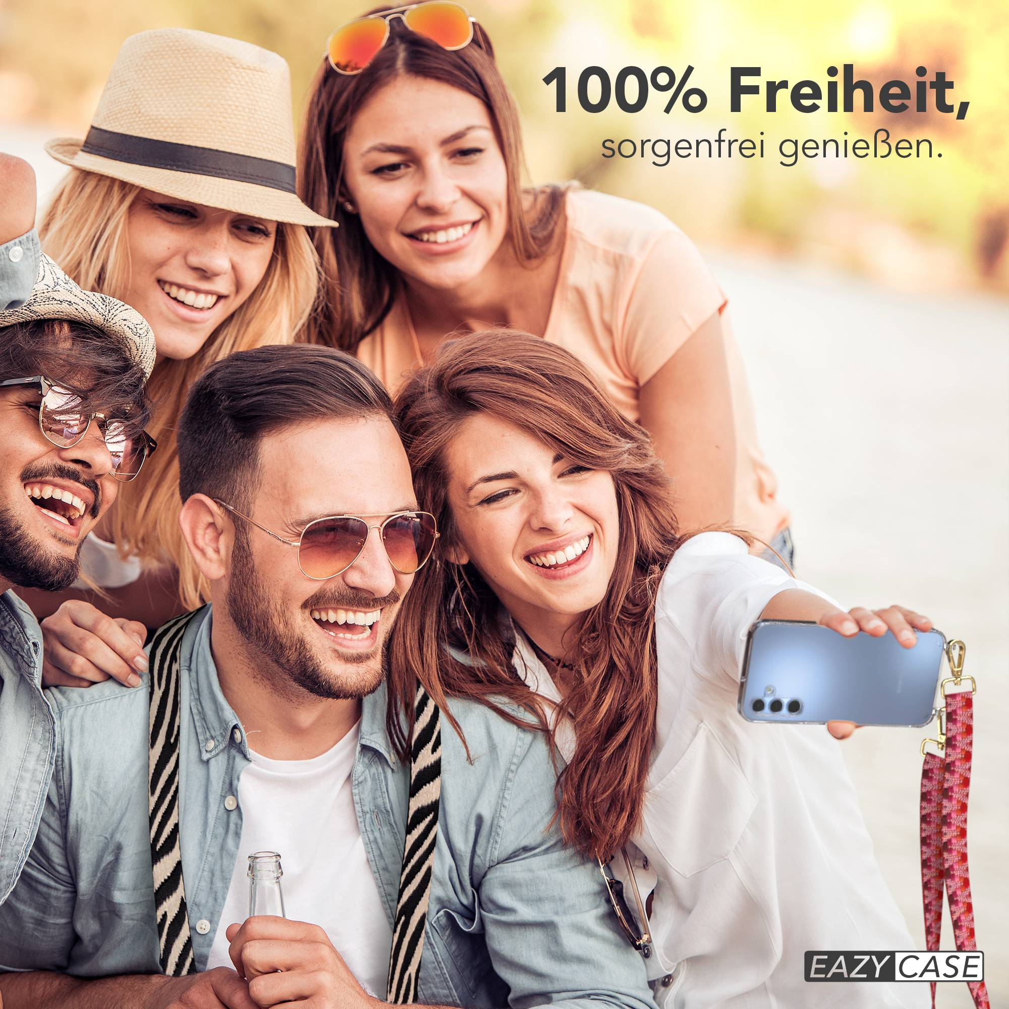 Vier lachende Freunde machen ein Selfie mit einem Handy in der Hand.