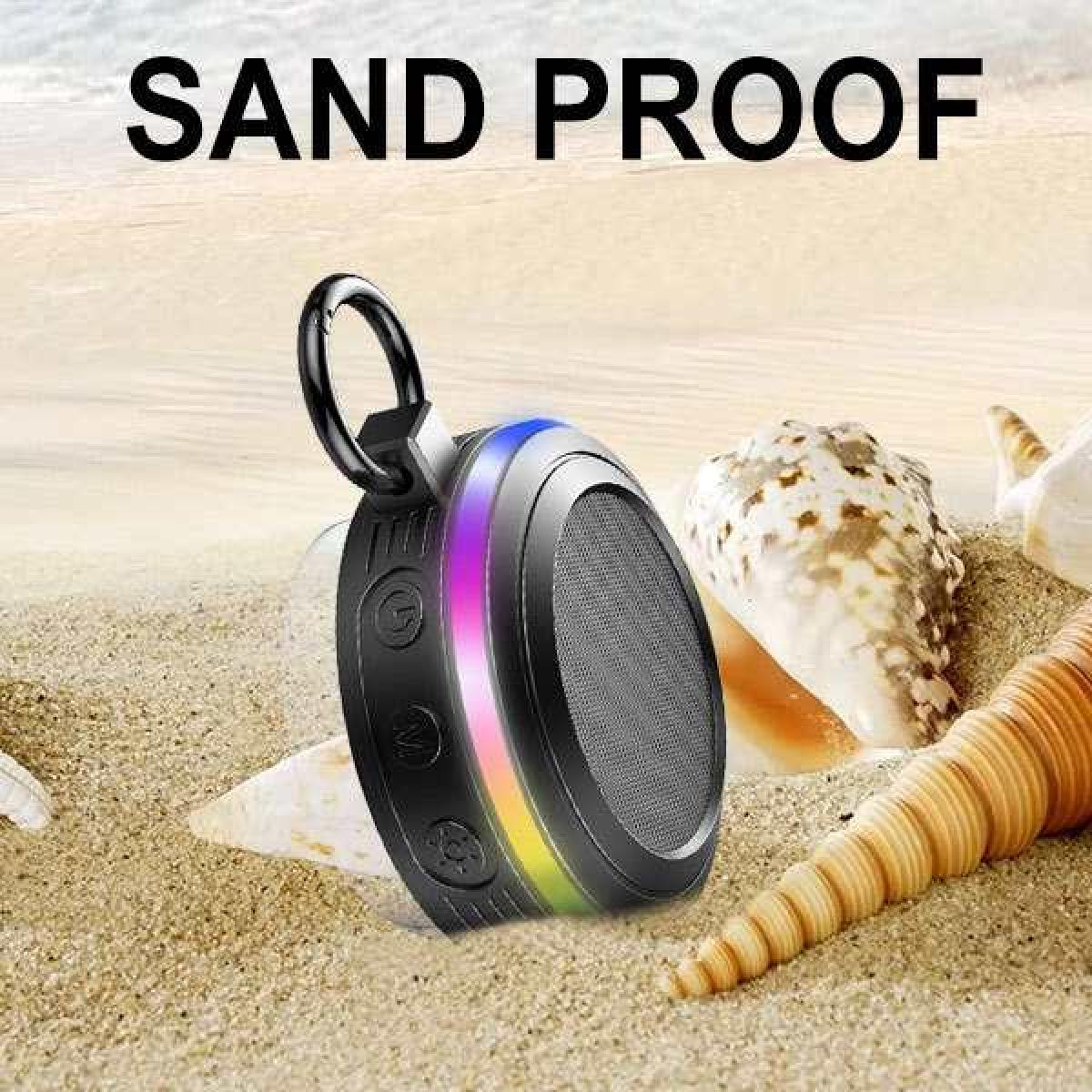Ein schwarzer Lautsprecher mit buntem Lichtring auf einem Sandstrand mit Muscheln.