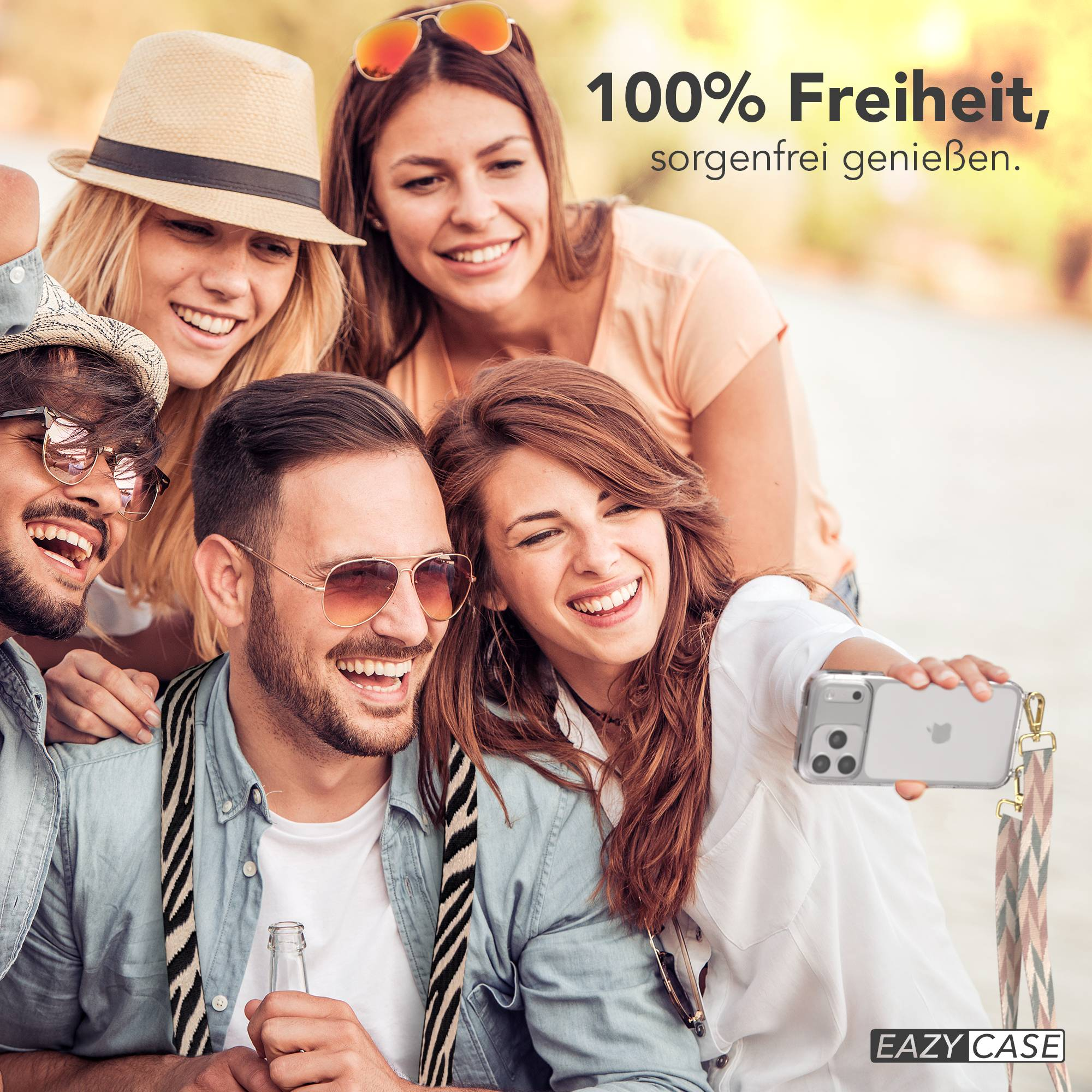 Vier lächelnde Freunde machen draußen ein Selfie. Einer hält ein Handy, ein anderer eine Flasche.