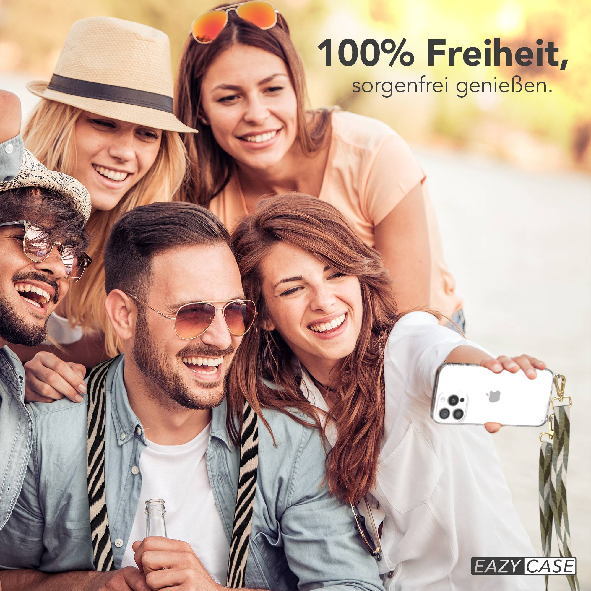 Vier Freunde lächeln und machen draußen ein Selfie, einer hält ein Handy.