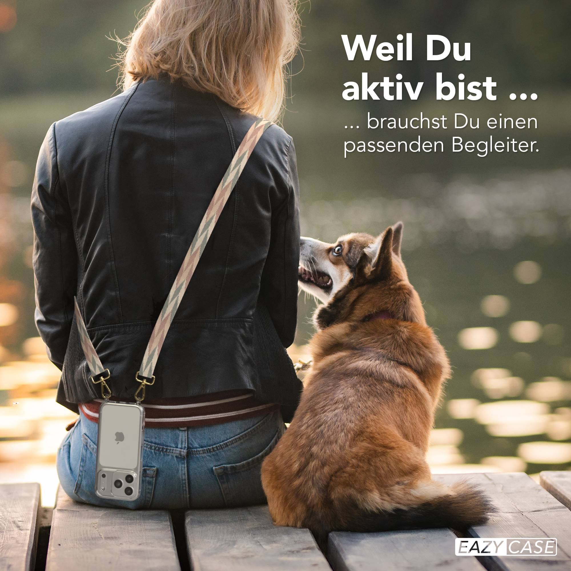 Ein Hund schaut eine Person an, die auf einer Holzbank sitzt. Das Handy hängt an einem Gurt.