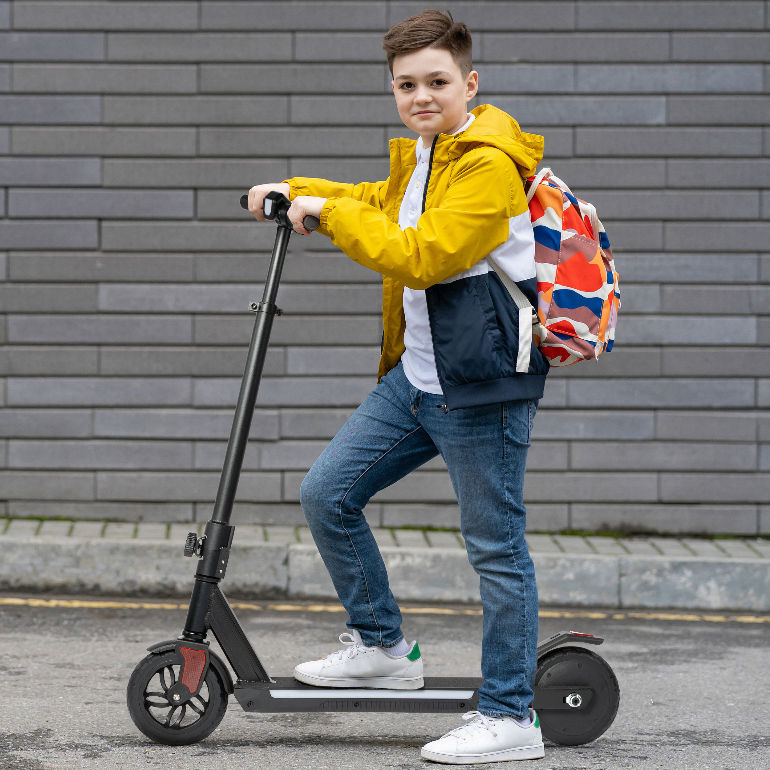Junge Person mit buntem Rucksack auf Elektroroller im Freien.