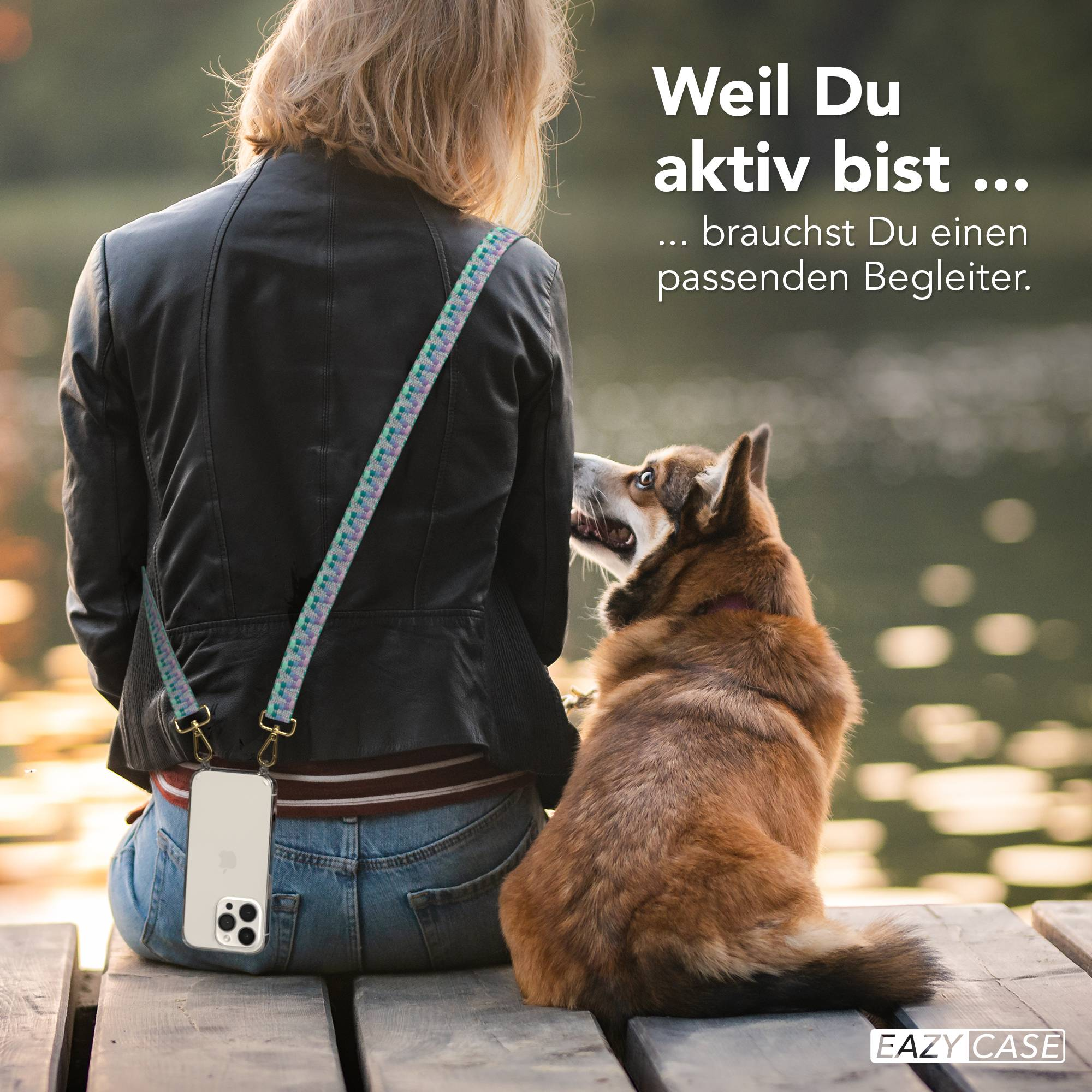 Frau mit Hund sitzt auf einer Holzplanke, Handy am Träger.