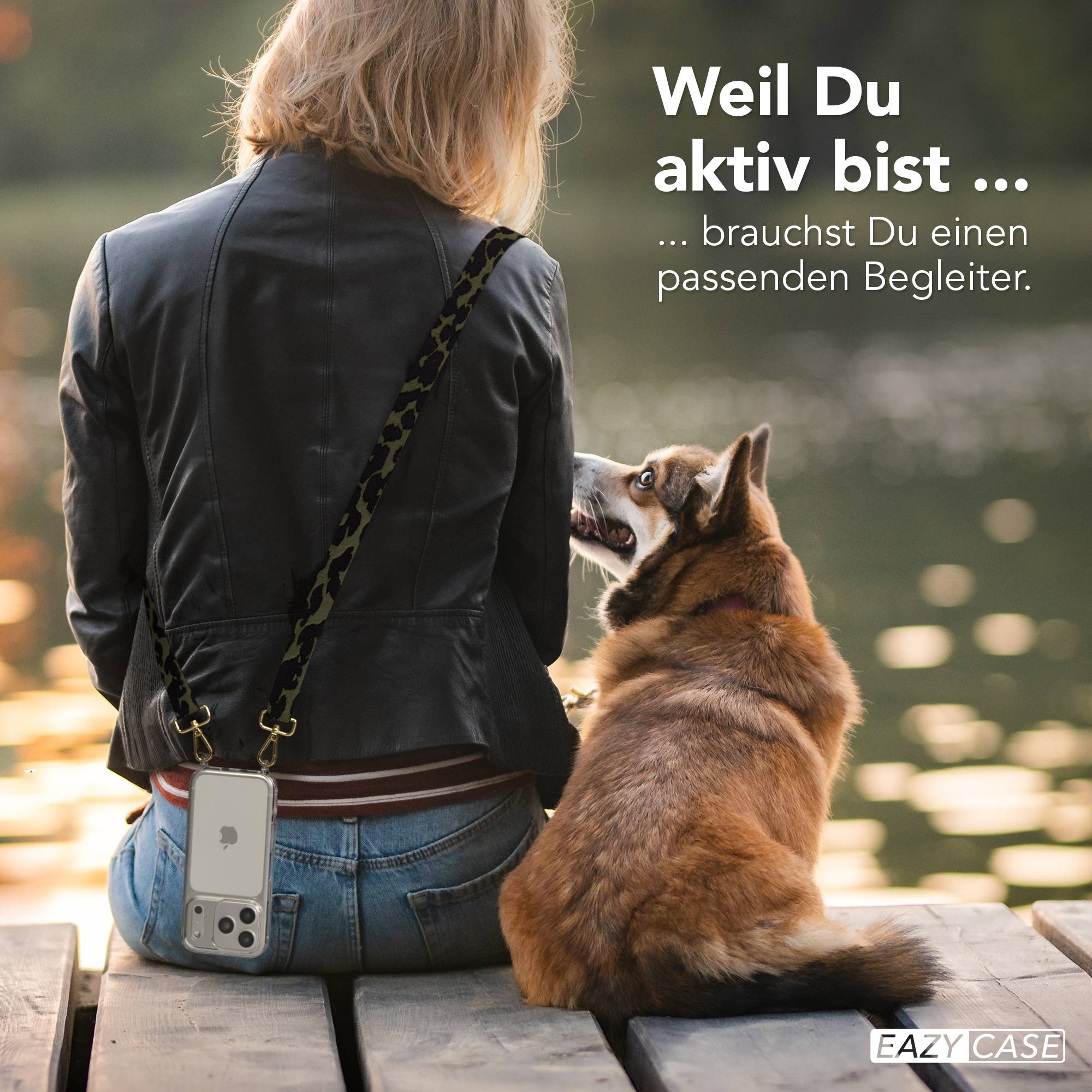 Eine Person sitzt auf einer Holzplattform, ein Hund schaut sie an. Ein Handy hängt von ihrer Schulter.