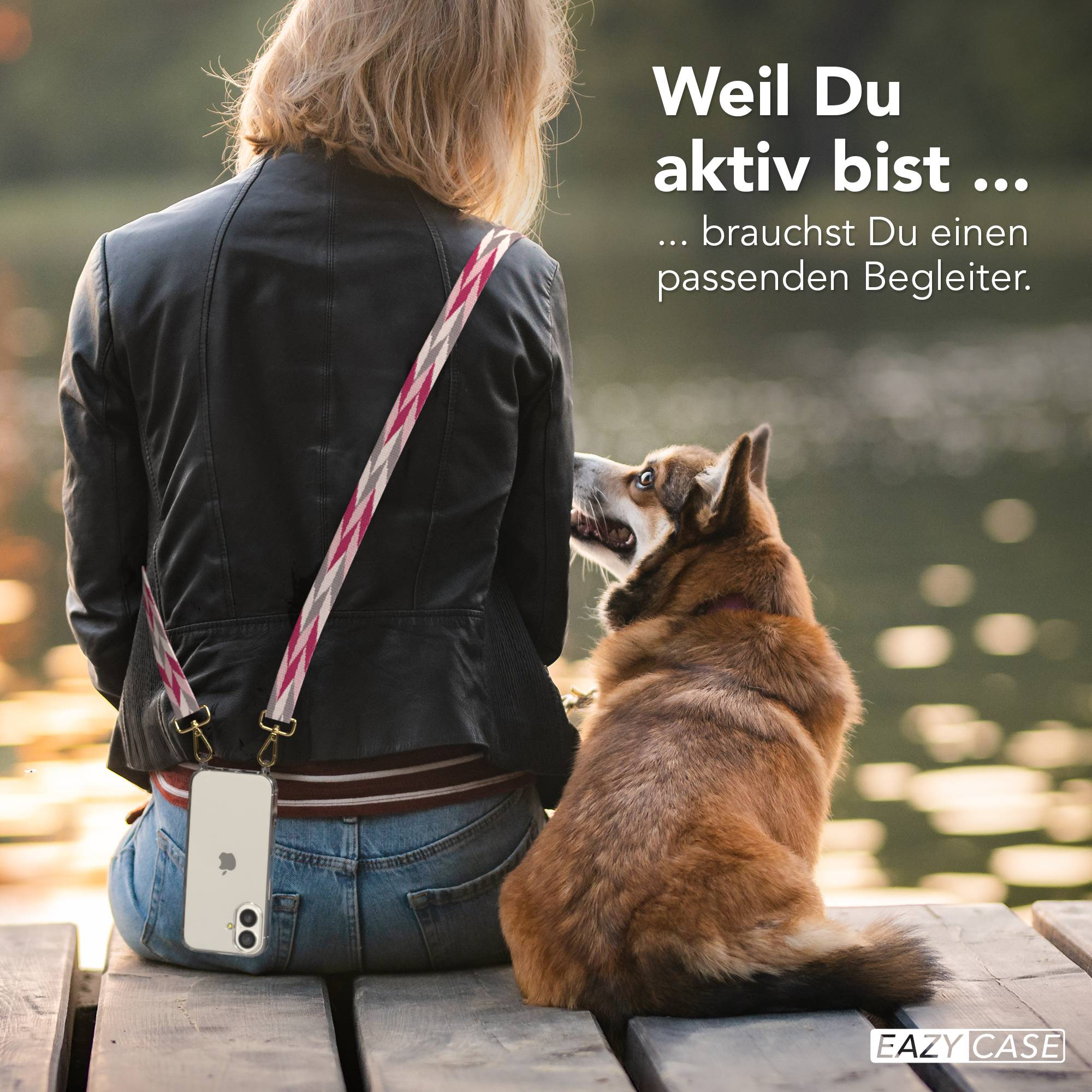 Eine Person mit Handy und Hund sitzt auf einer Holzbrücke am See.