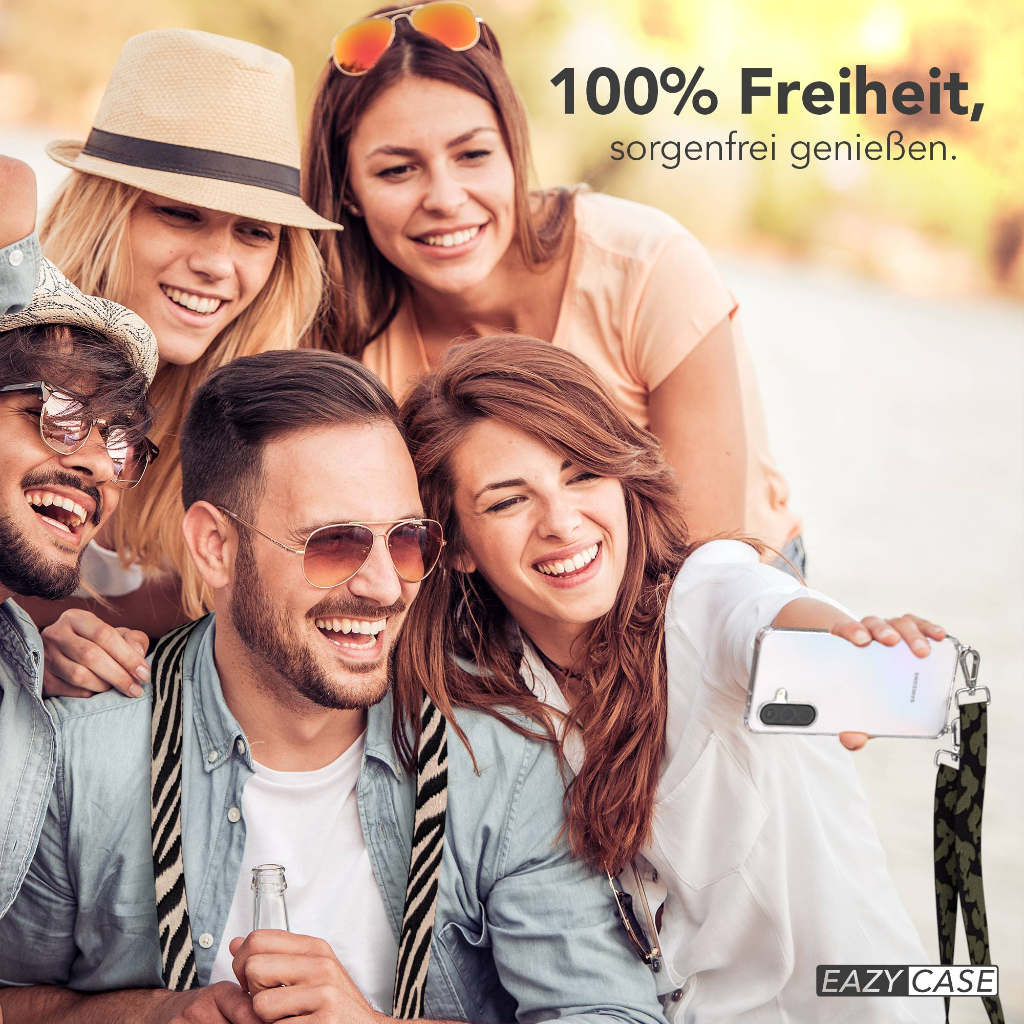 Vier Freunde machen draußen ein Selfie, lächelnd, mit Handy und Flasche.