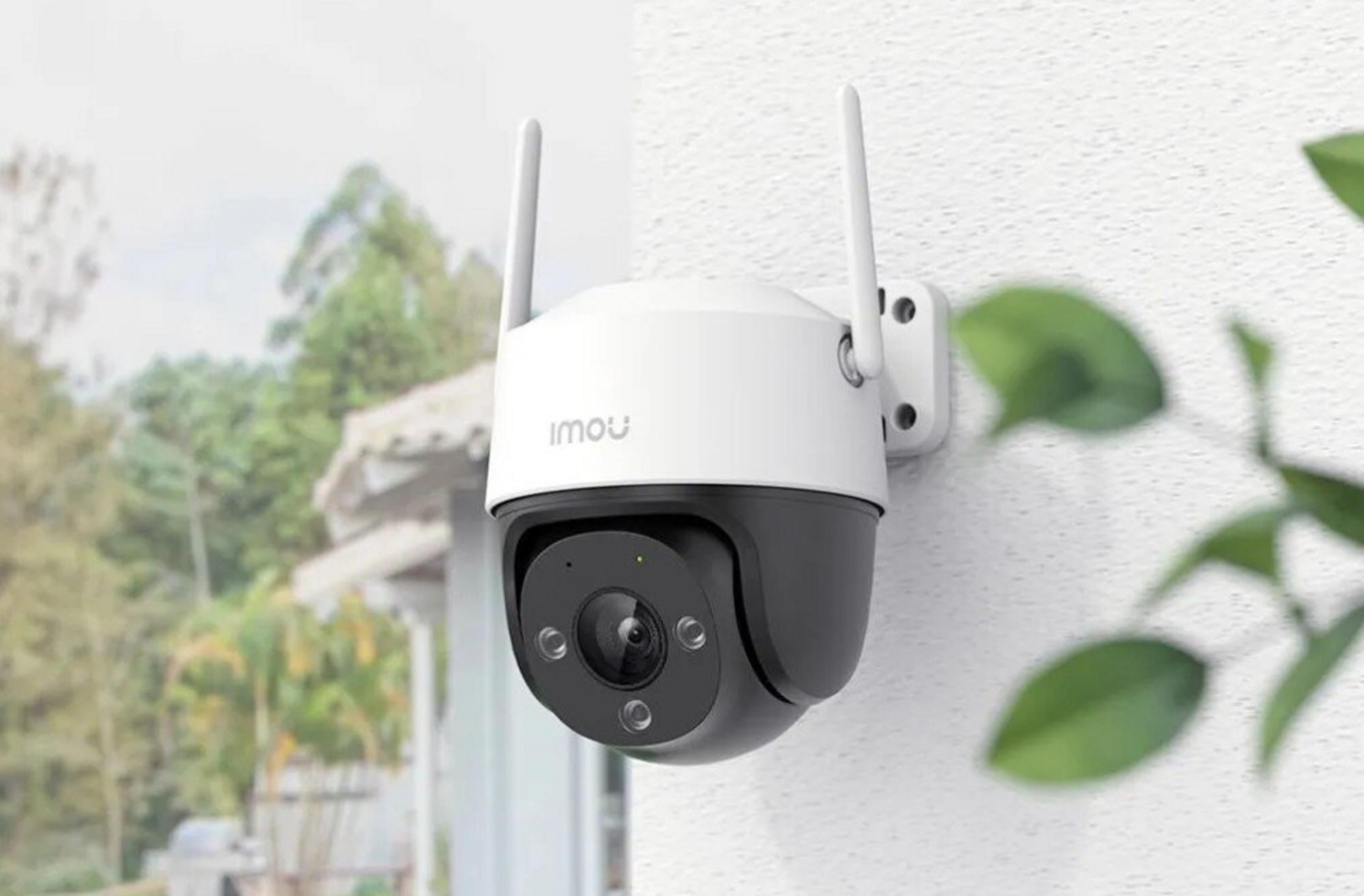 Una telecamera di sicurezza bianca e nera con antenne montata su un muro.