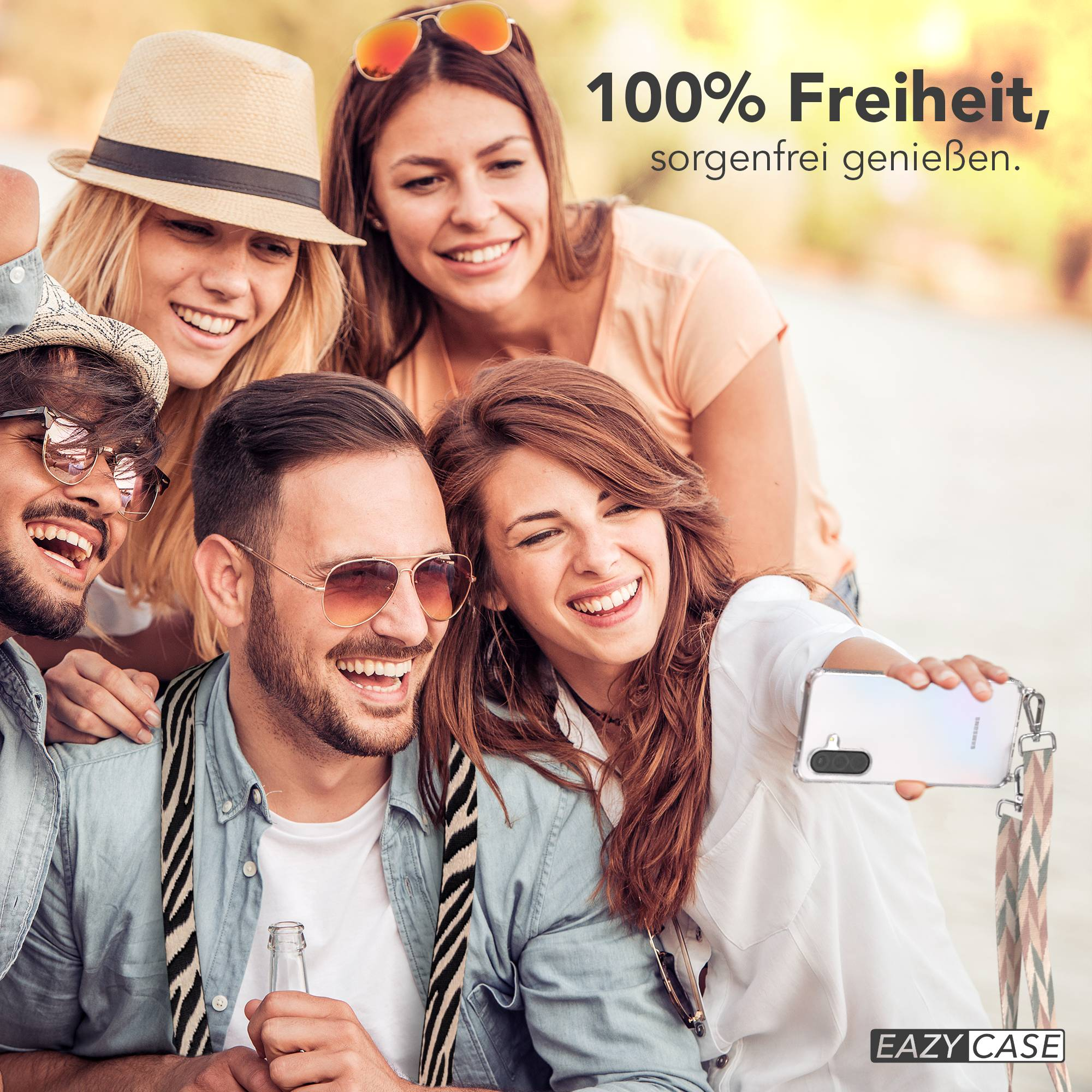 Vier Freunde machen draußen ein Selfie. Einer hält ein Handy und eine Flasche.