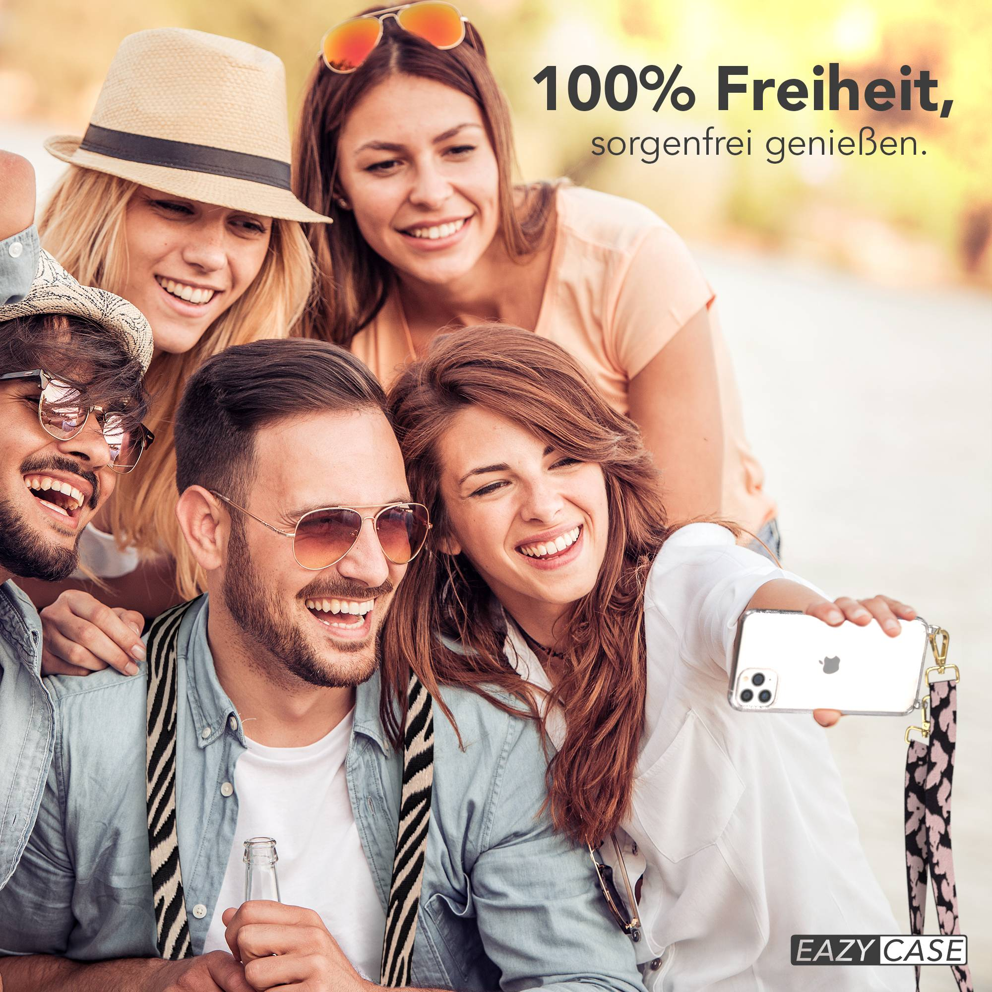 Vier lachende junge Leute machen ein Selfie im Freien. Eine Frau hält das Handy.