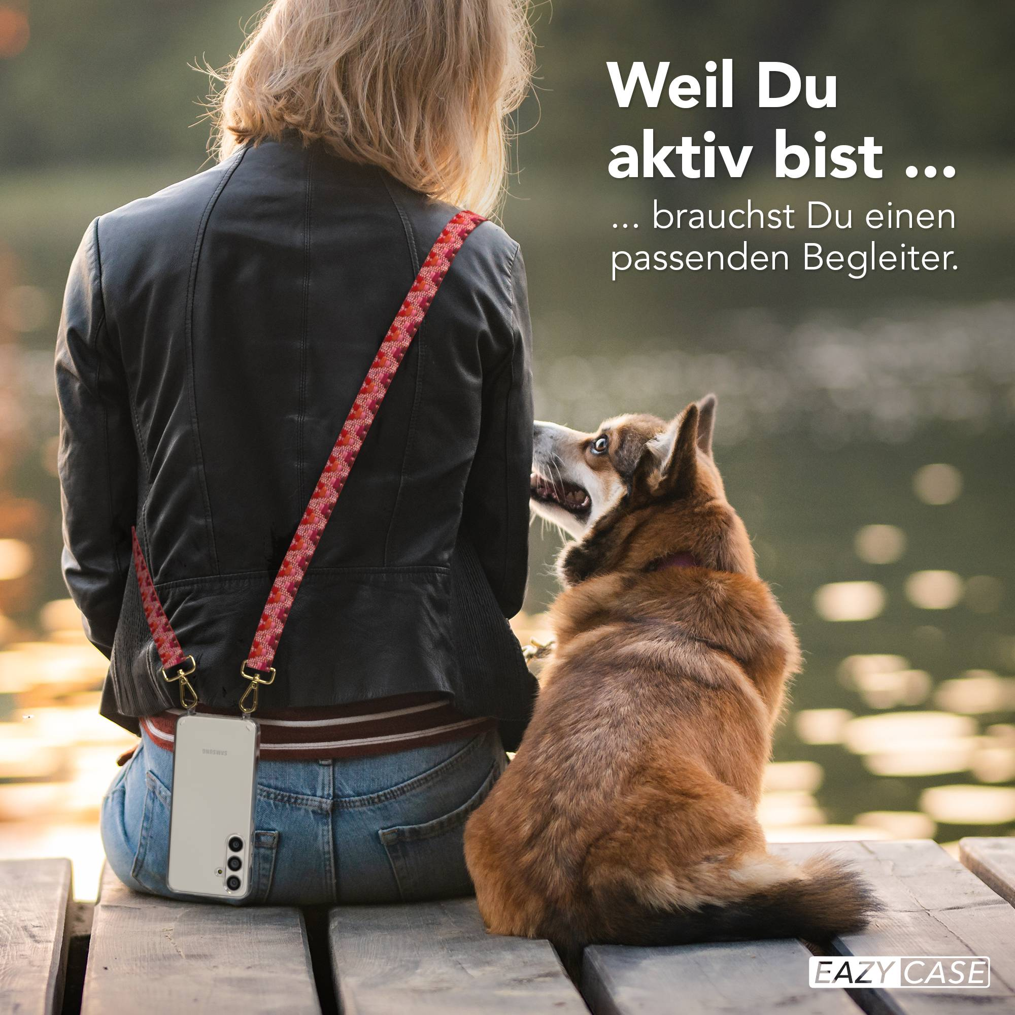 Eine Frau mit Hund sitzt auf einer Holzplanke, eine Tasche ist um den Hals.