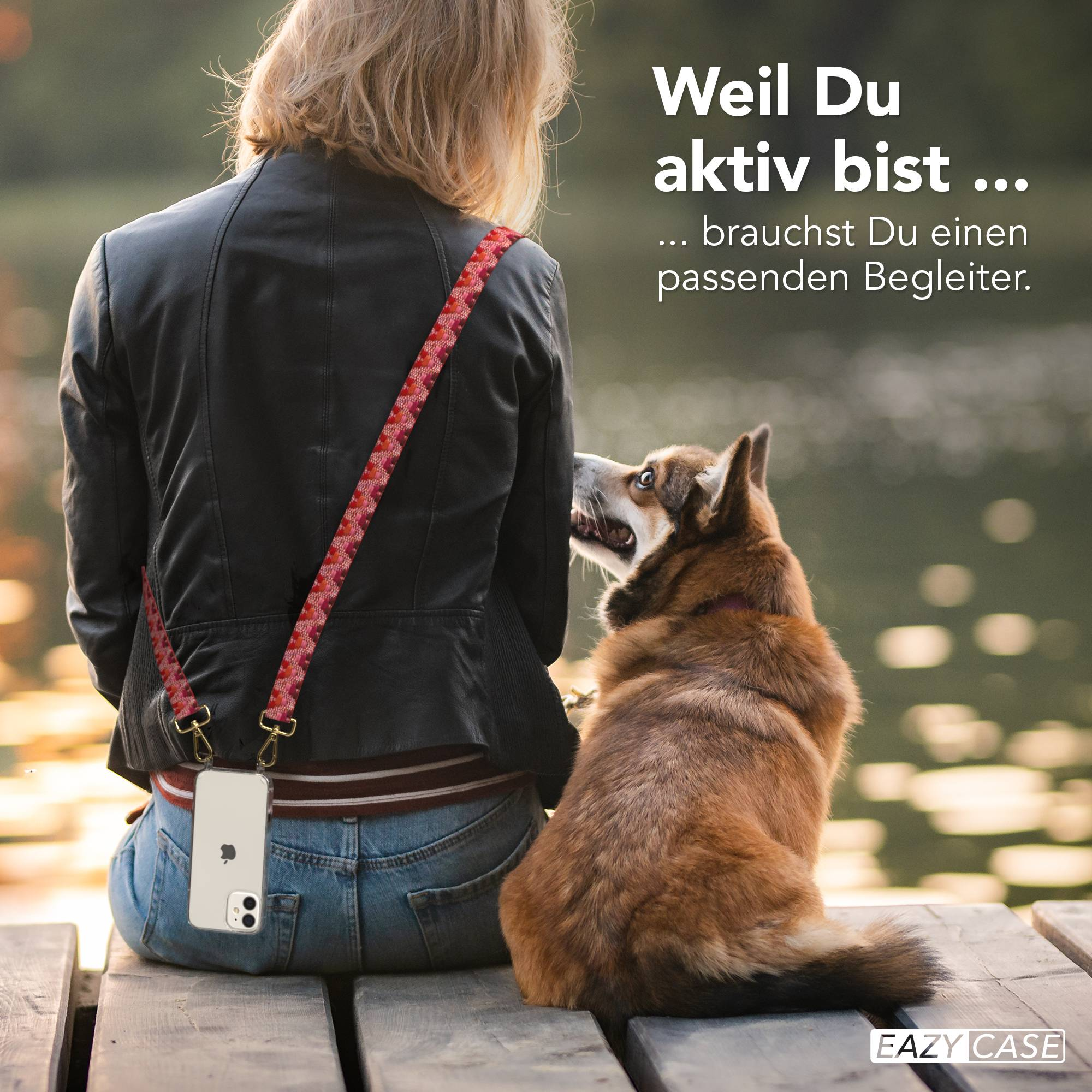Eine Frau mit Handy an einem Gurt sitzt auf einem Holzsteg mit einem Hund, der zu ihr aufblickt.